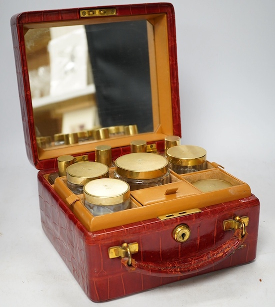 An early 20th century crocodile skin vanity case with glass jars, 21.5cm wide. Condition - fair, no key                                                                                                                     