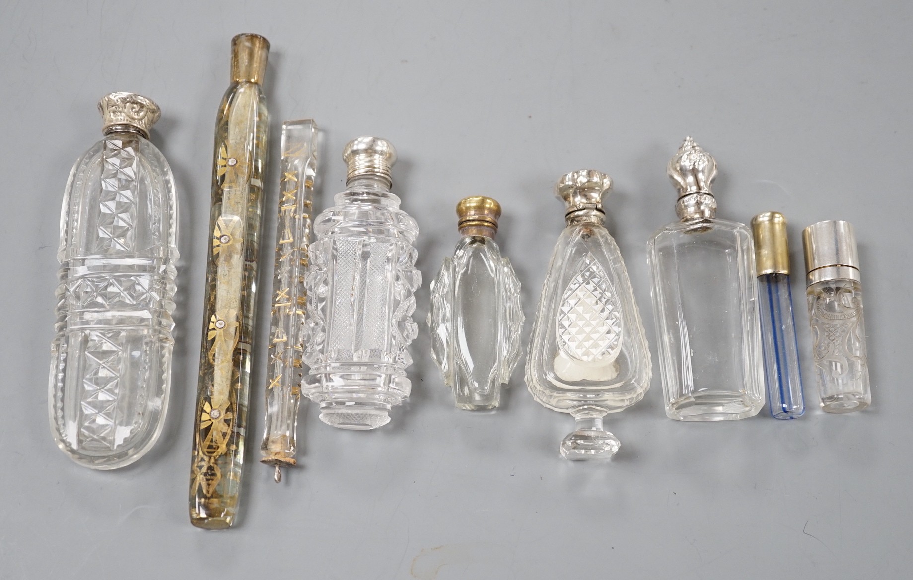 Nine assorted late 19th/early 20th century white or gilt white metal mounted glass scent bottles, including Austro-Hungarian gilt white metal and enamel mounted cylindrical scent by George Adam Scheid, largest 17.2cm.   