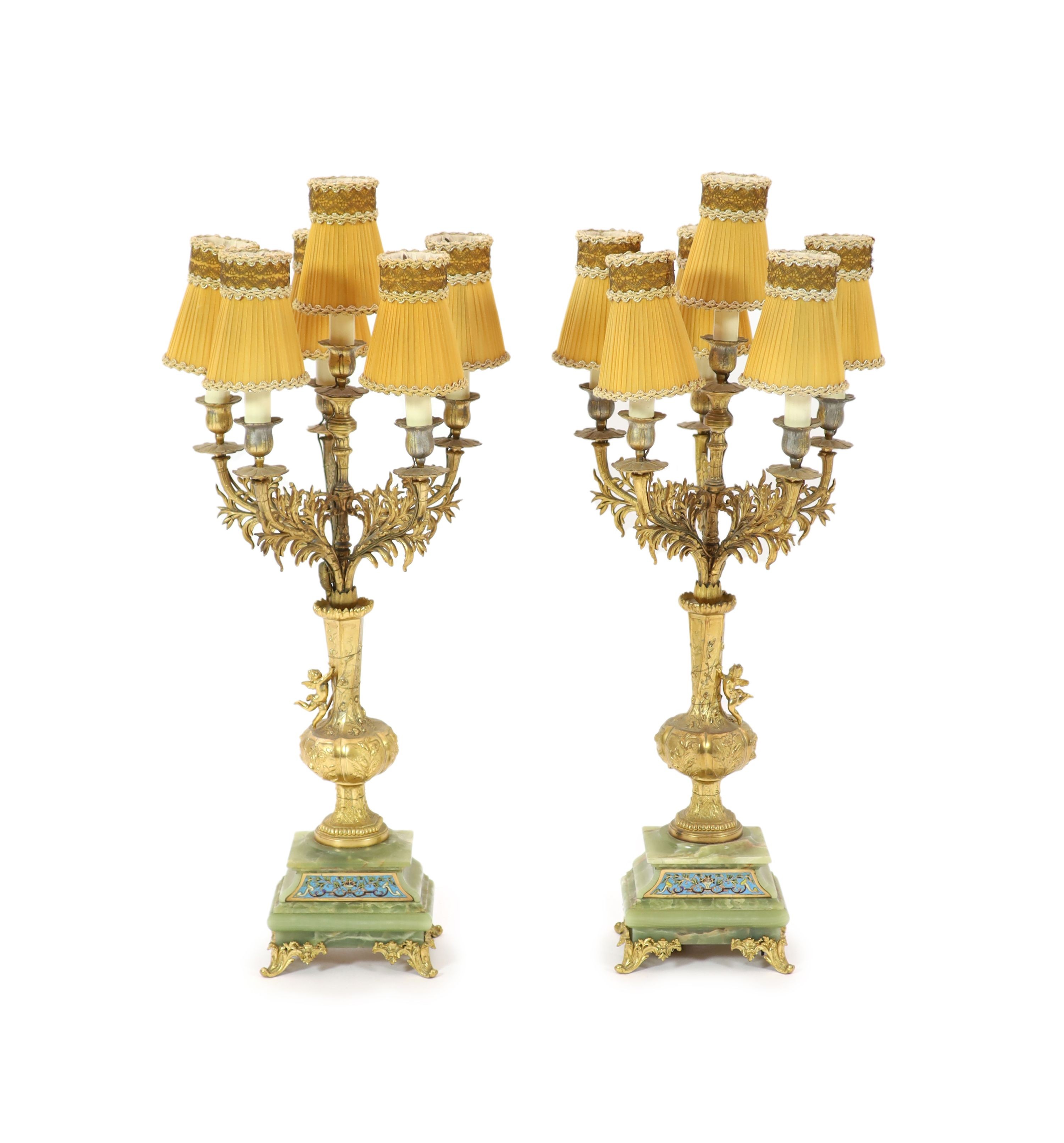 A pair of elaborate gilt metal and green onyx six-light candelabra table lamps on pedestal urn supports incorporating champlevé enamel plaques H 70cm.                                                                      