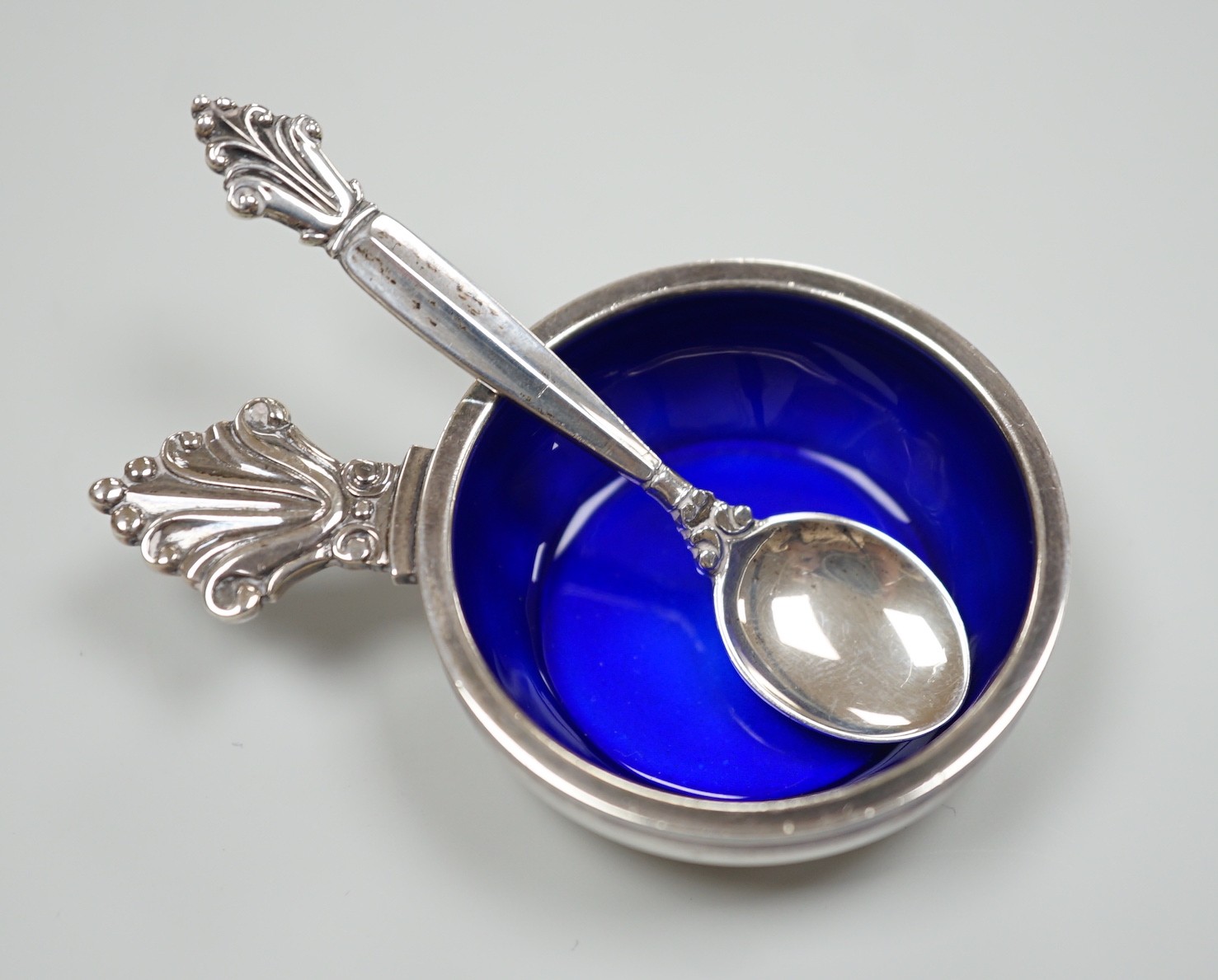A modern Georg Jensen silver and enamel salt, design no. 180, 63mm and matching salt spoon, 64mm, gross weight 29.3 grams.                                                                                                  
