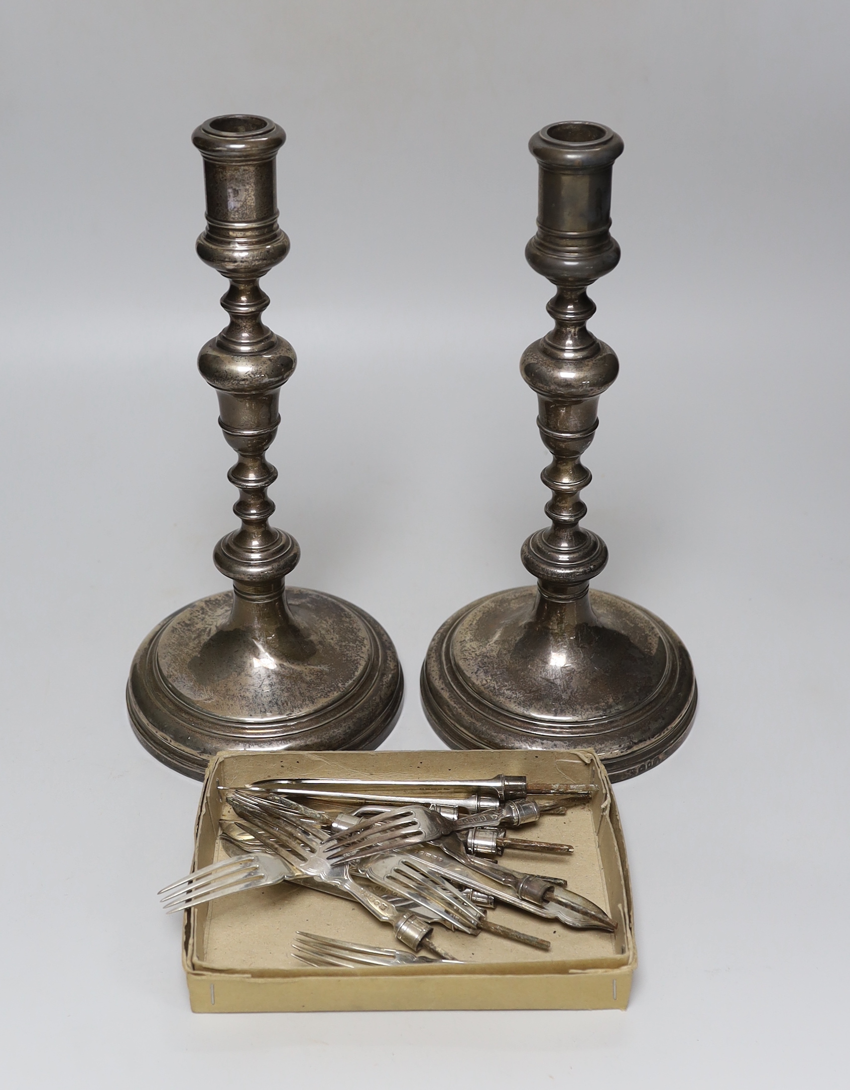 A pair of George V silver candlesticks, by William Comyns & Sons Ltd, London, 1930, height 29.6cm, weighted and eight pairs of silver fish eaters (no handles).                                                             