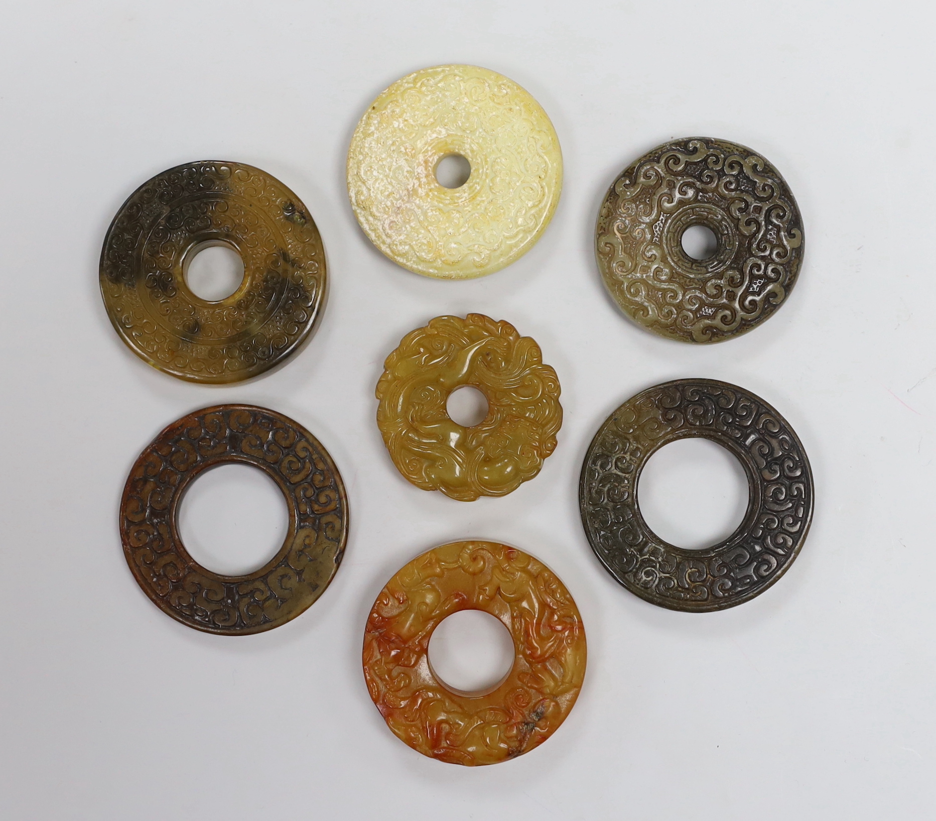 Seven Chinese jade or hardstone bi discs with carved decoration, the largest 5cm in diameter                                                                                                                                