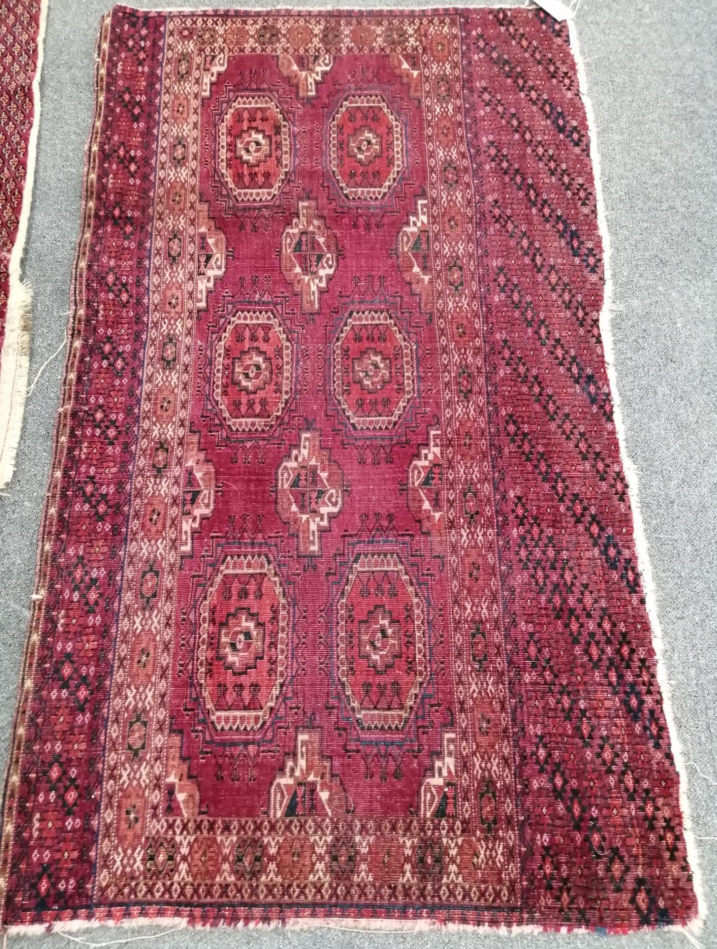 A Tekke burgundy ground rug, 135 x 77cm, worn                                                                                                                                                                               