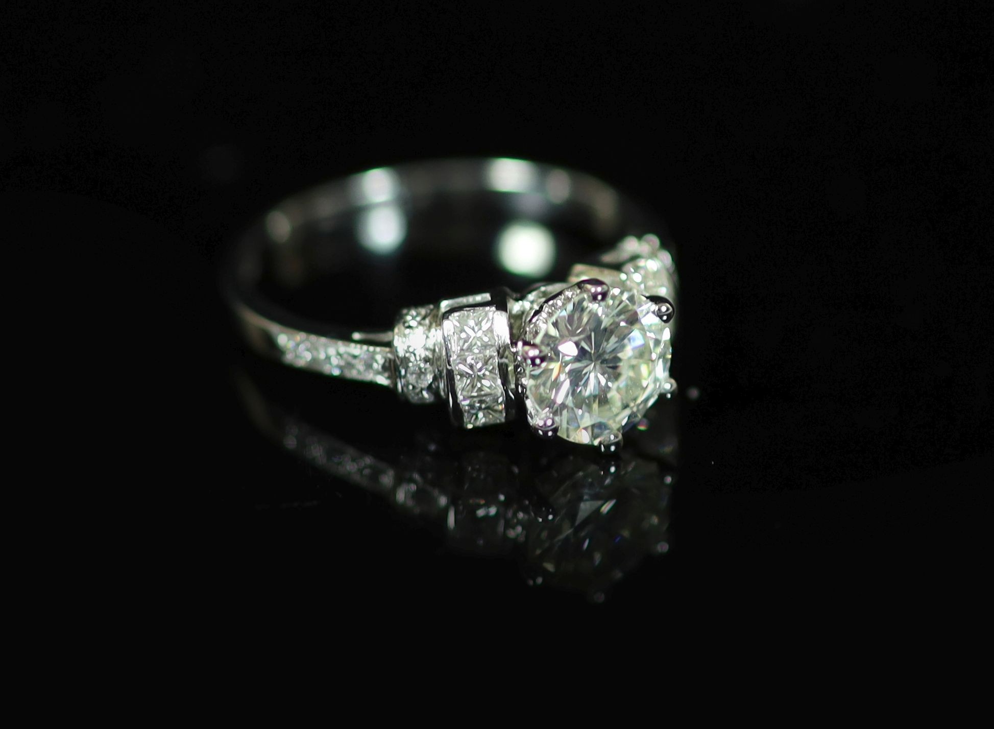 A modern platinum and single stone diamond ring centre with fancy and round cut diamond set shoulders                                                                                                                       