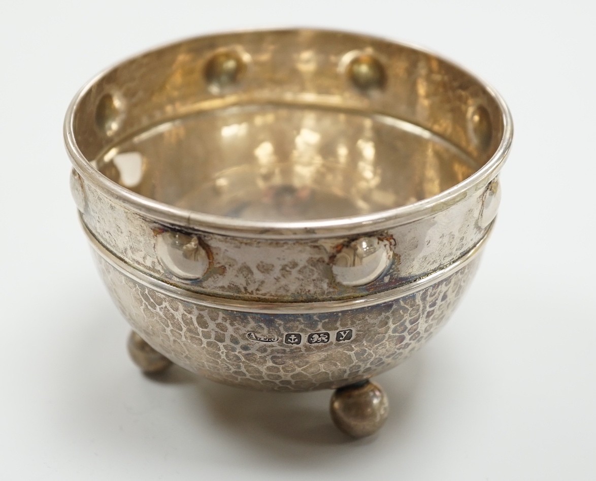 A George V Arts Crafts planished silver bowl, by Albert Edward Jones, Birmingham, 1923, diameter 92mm, on three ball feet, 4oz.                                                                                             