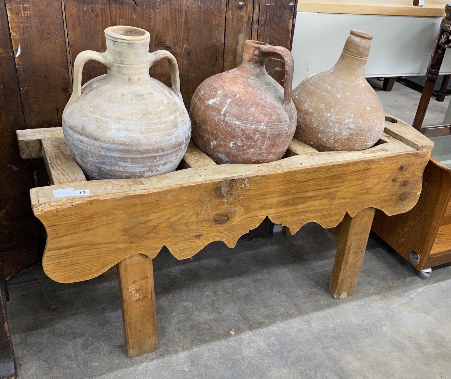 Three Mediterranean pottery olive jars on a rectangular pine stand, stand width 116cm, depth 41cm, height 56cm                                                                                                              