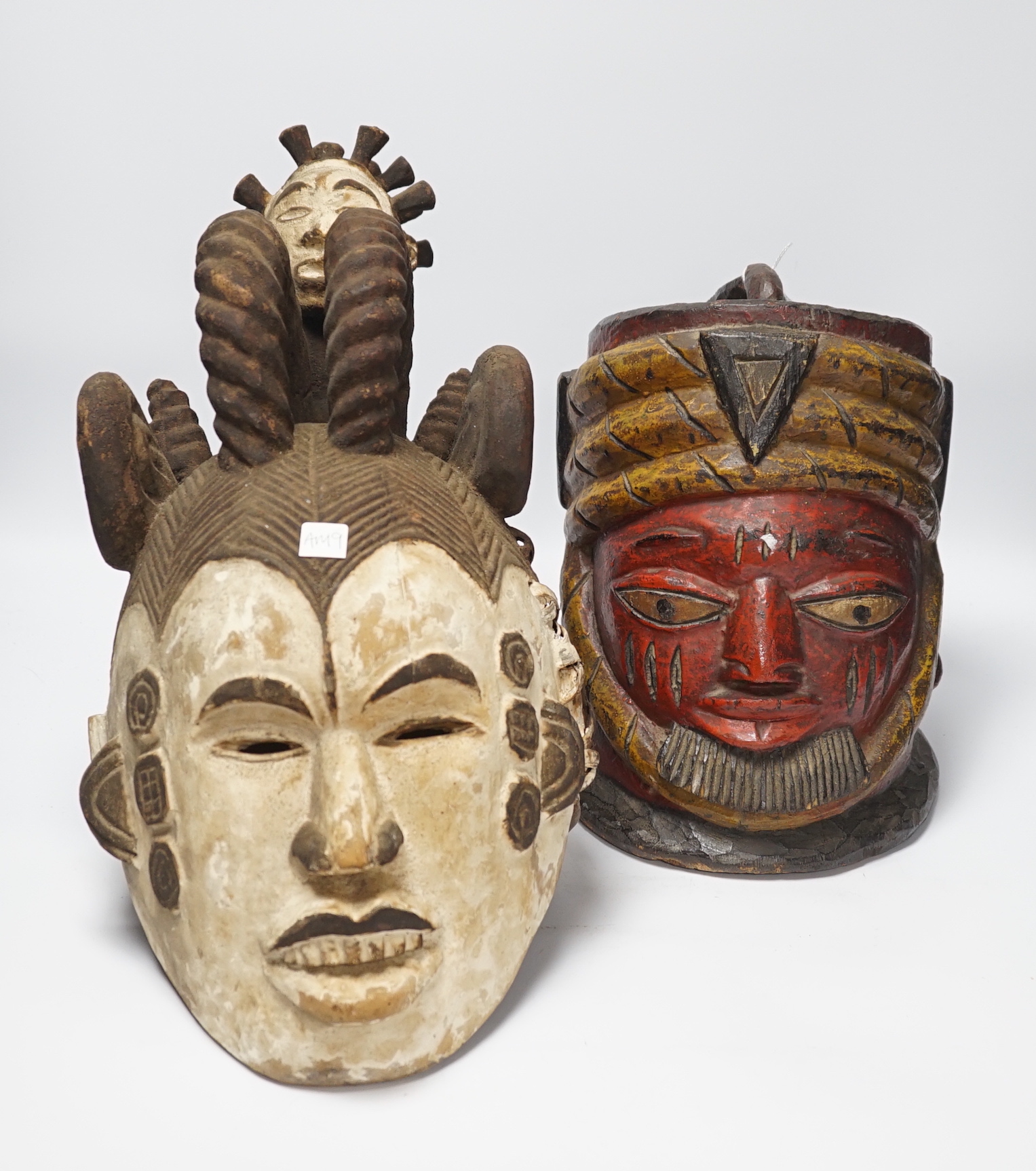 An Igbo maiden spirit mask and an African tribal helmet mask, largest 46cm wide                                                                                                                                             