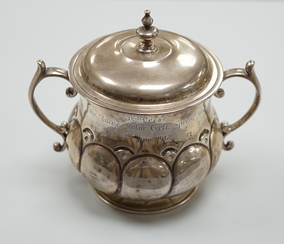 A George V silver presentation porringer and cover for the 'Rudge Motorcycle Sprint Race at Brooklands 13th of June 1912, third prize' William Comyns, height 10.5cm, 6.1oz.                                                