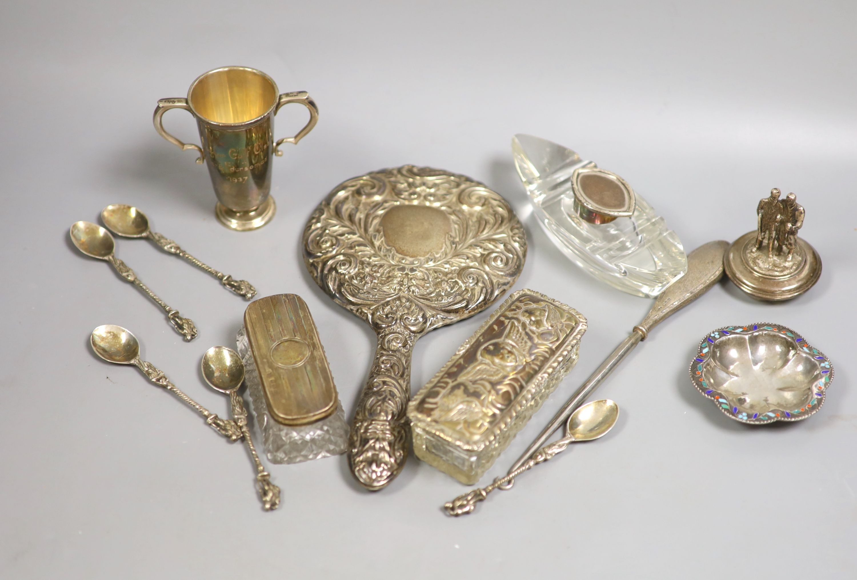 Small silver including a hand mirror, two mounted glass toilet jars, two handled golfing related trophy cup, silver spoons, white metal and enamel dish etc.                                                                