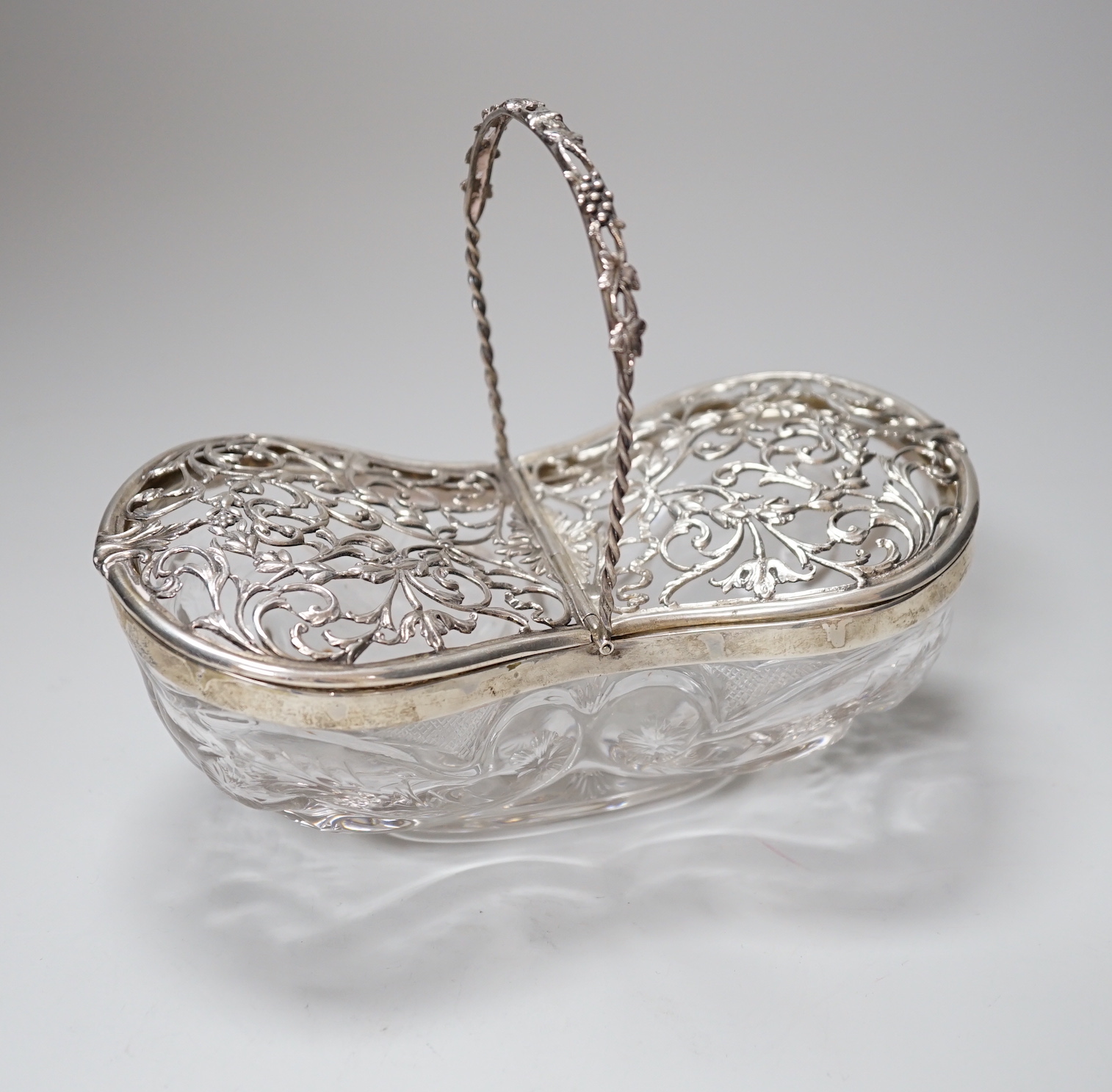 A George V silver mounted Stoubridge glass bon bon basket, with swing handle and two foliate scroll pierced hinged lids, Charles & Richard Comyns, London 1918, 17cm                                                        