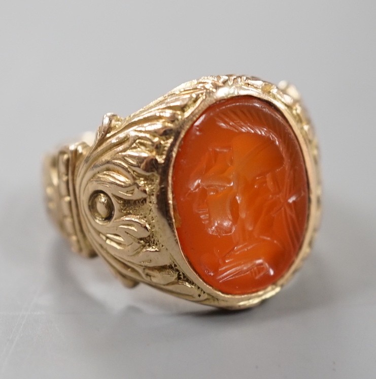 An early 20th century yellow metal and intaglio carnelian set signet ring, the matrix carved with the bust of a Roman soldier, with carved setting and shank, size M, gross weight 9.6 grams.                               