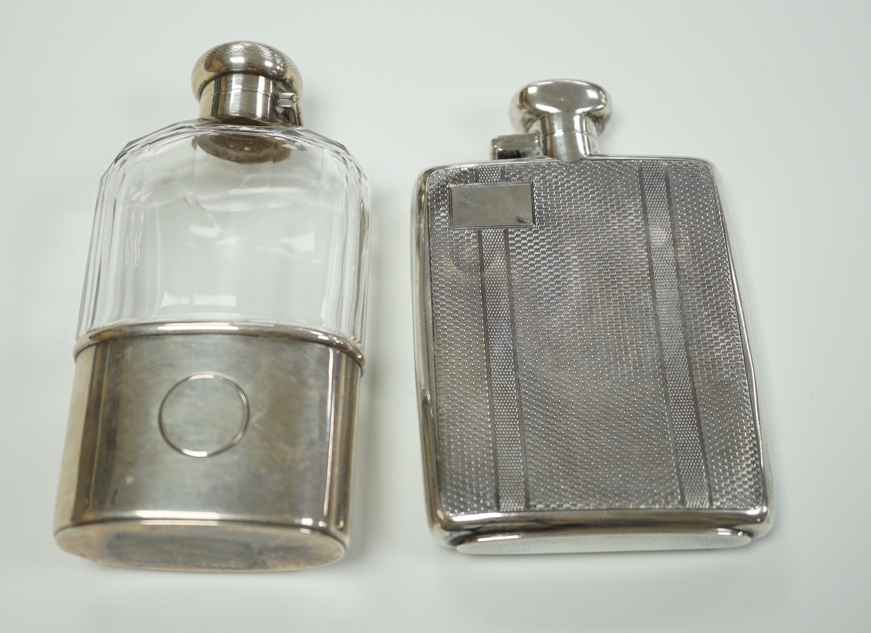 A George V engine turned silver hip flask, by Robert Pringle & Sons, Chester, 1929, 12.8cm and an earlier silver mounted glass hip flask, London, 1910.                                                                     