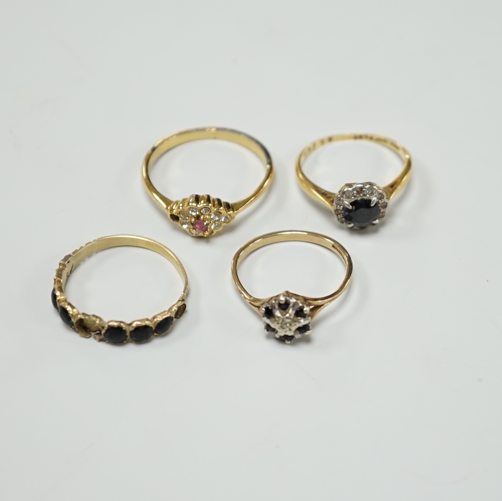 Four assorted diamond and gem set dress rings, comprising an 18ct gold sapphire and diamond cluster, size M, a gilt metal paste lacking one stone, size R, a 9ct gold diamond chip and sapphire, size L and an unmarked jet 