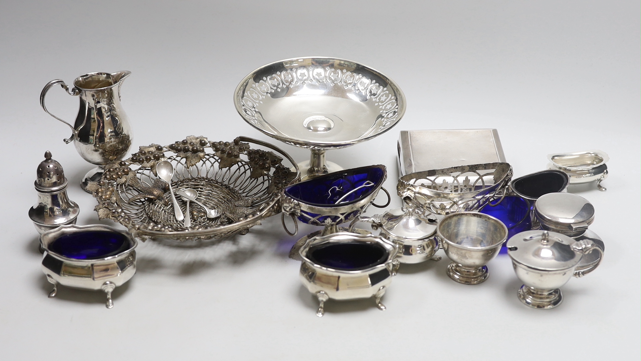 Assorted silver etc, including a George III sparrow beak cream jug, Thomas & Richard Payne, London, 1779, condiments, cigarette box, weighted tazze, etc.                                                                   