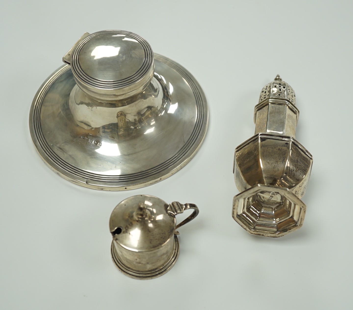 A George V silver octagonal sugar caster, Sheffield, 1910, 15.9cm, a George V silver mounted capstan inkwell and a small silver mustard pot.                                                                                