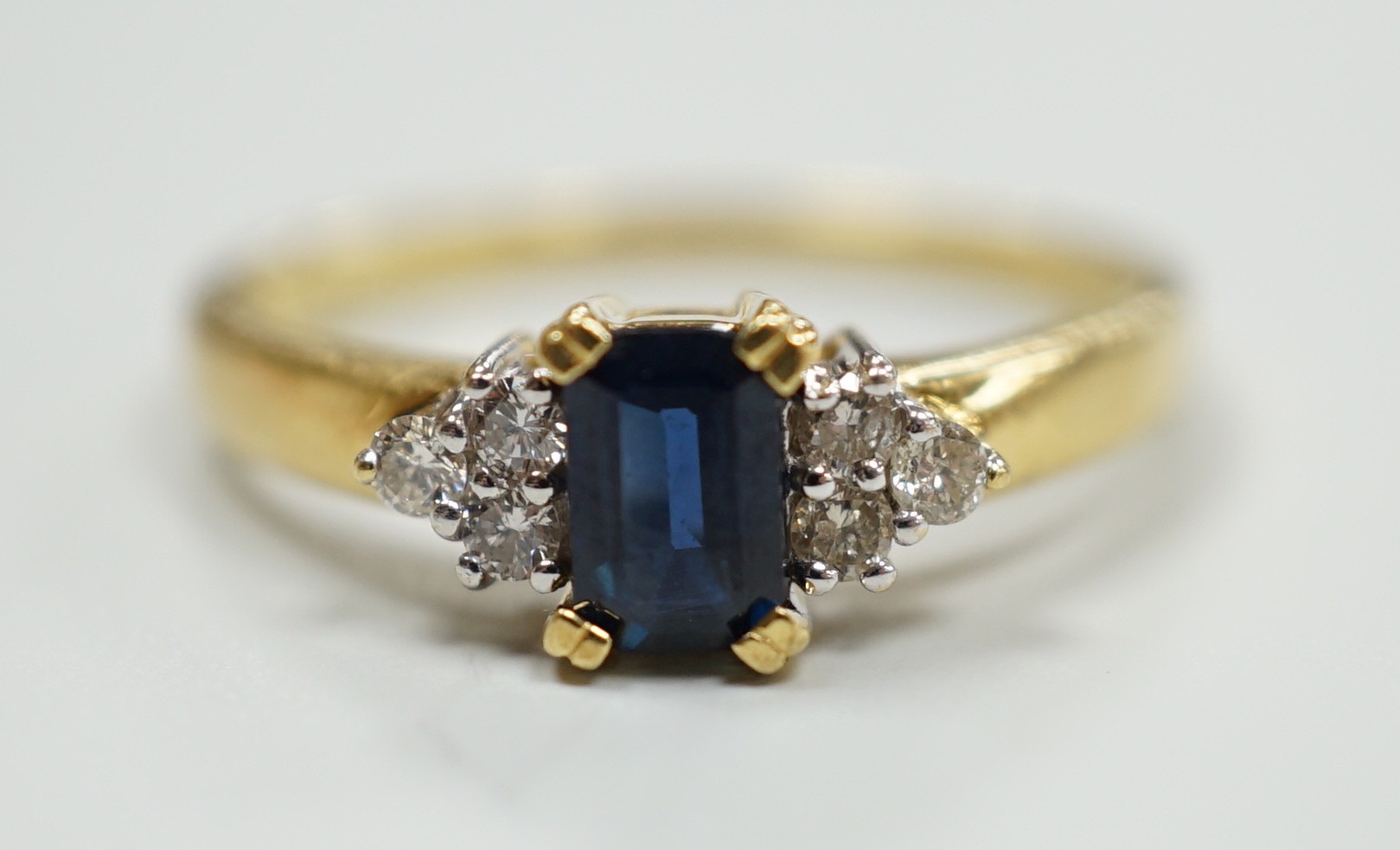 A modern 18ct gold and single stone sapphire set ring, with six stone diamond set shoulders, size R, gross weight 3.2 grams.                                                                                                