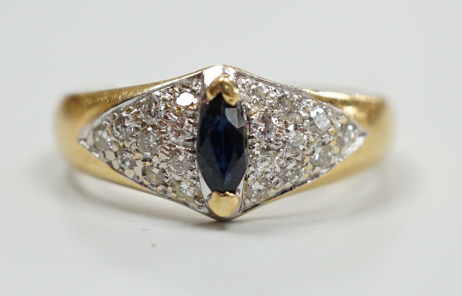 A modern 18ct gold and single stone marquise cut sapphire set dress ring, with pave set diamond shoulders, size R, gross weight 5 grams.                                                                                    