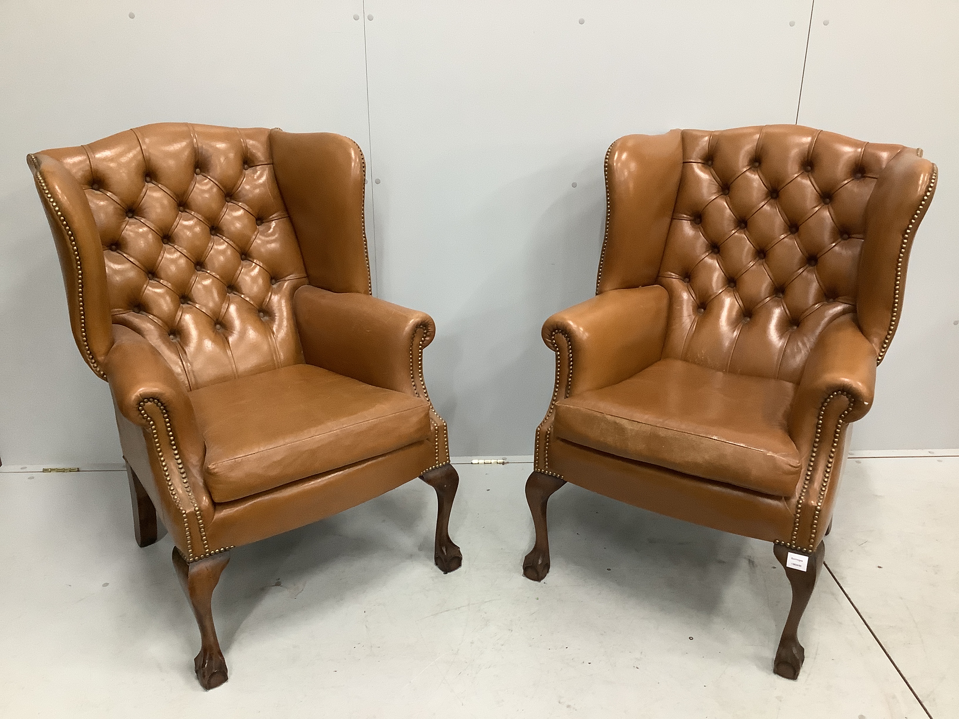 A pair of reproduction George III style buttoned pale brown leather wing armchairs, width 75cm, depth 66cm, height 107cm                                                                                                    