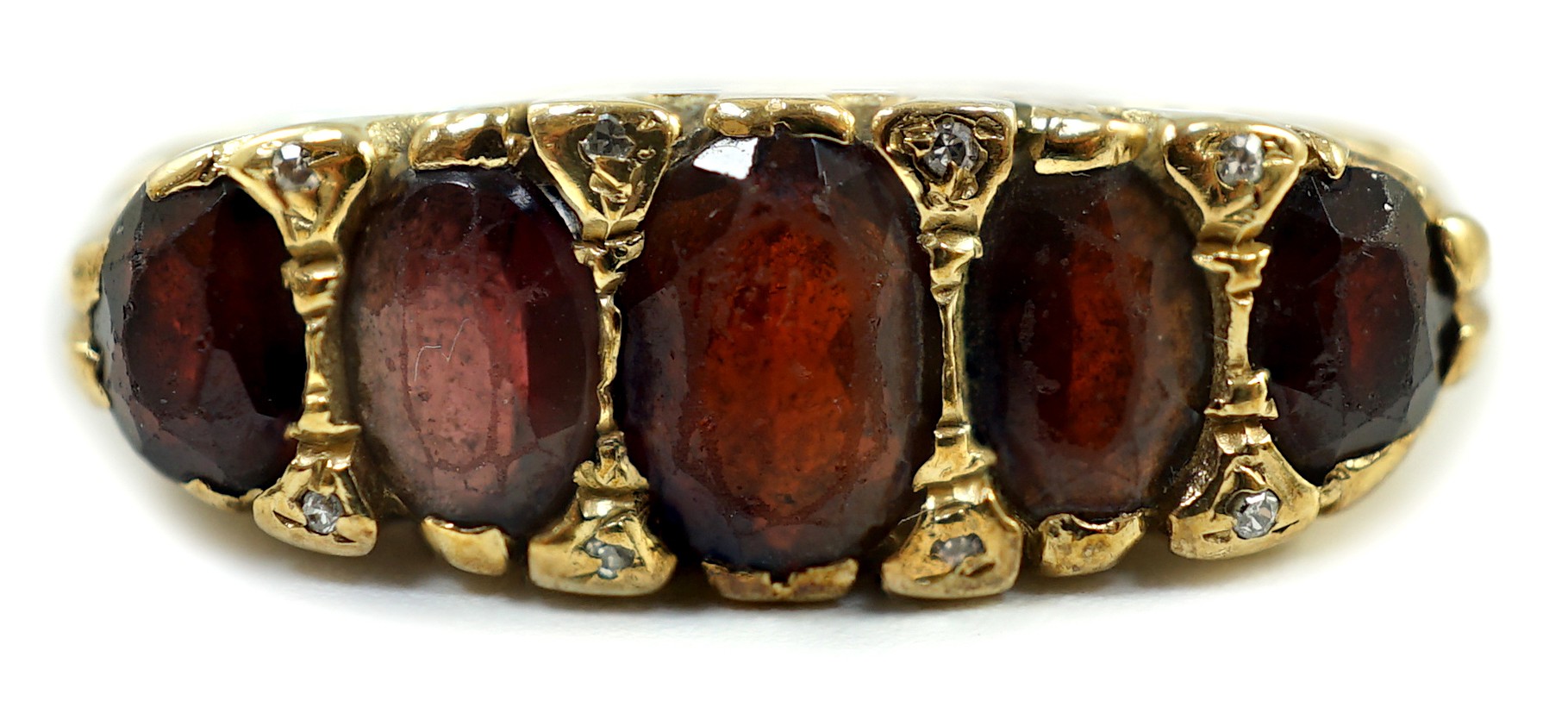 A 1960's Victorian style 9ct gold and graduated five stone garnet set half hoop ring, with diamond chip spacers, size V, gross weight 6 grams.                                                                              