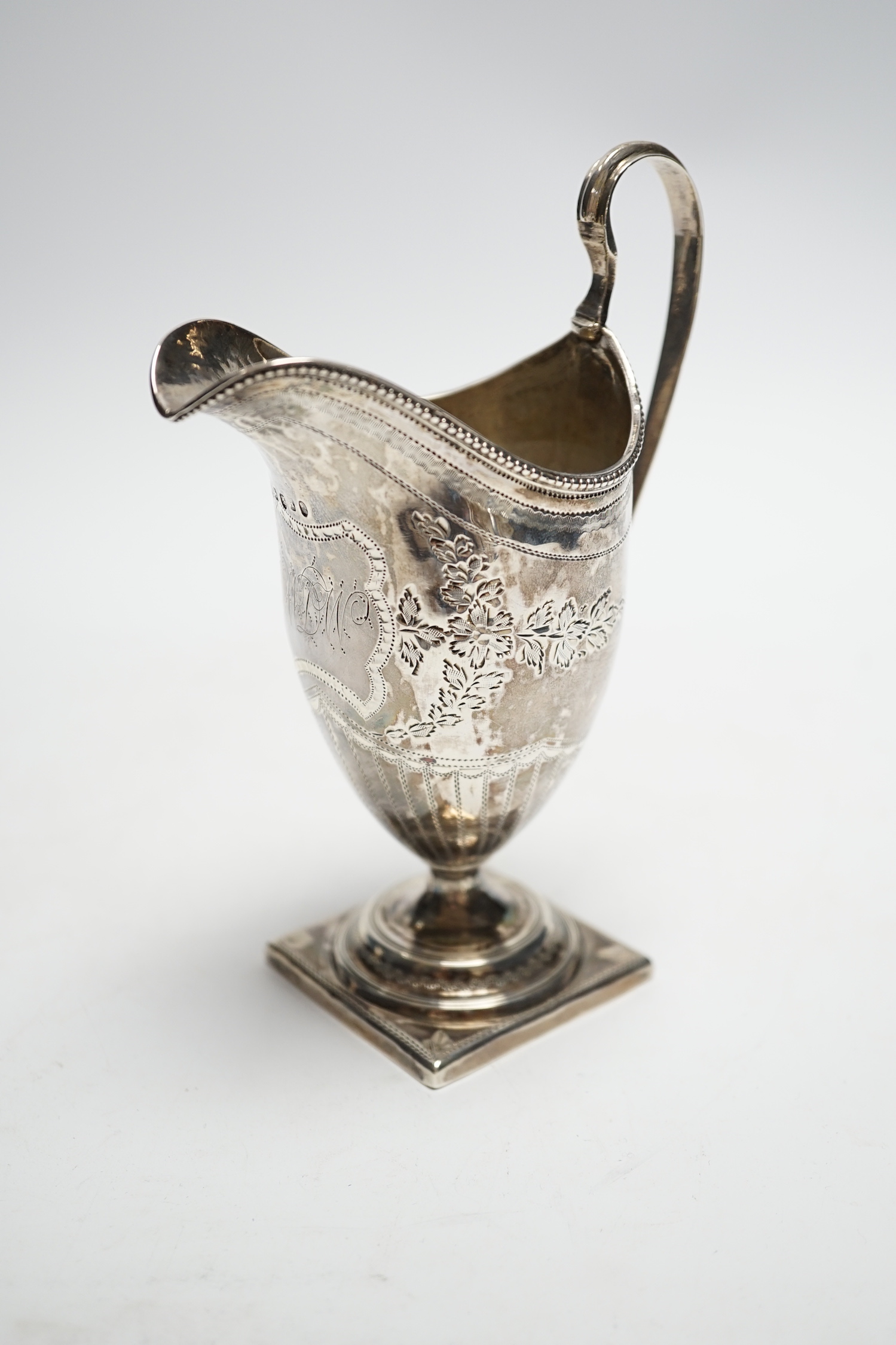 A George III engraved silver helmet shaped cream jug, on square foot, Soloman Hougham, London, 1796, 15cm, 3.6oz.                                                                                                           