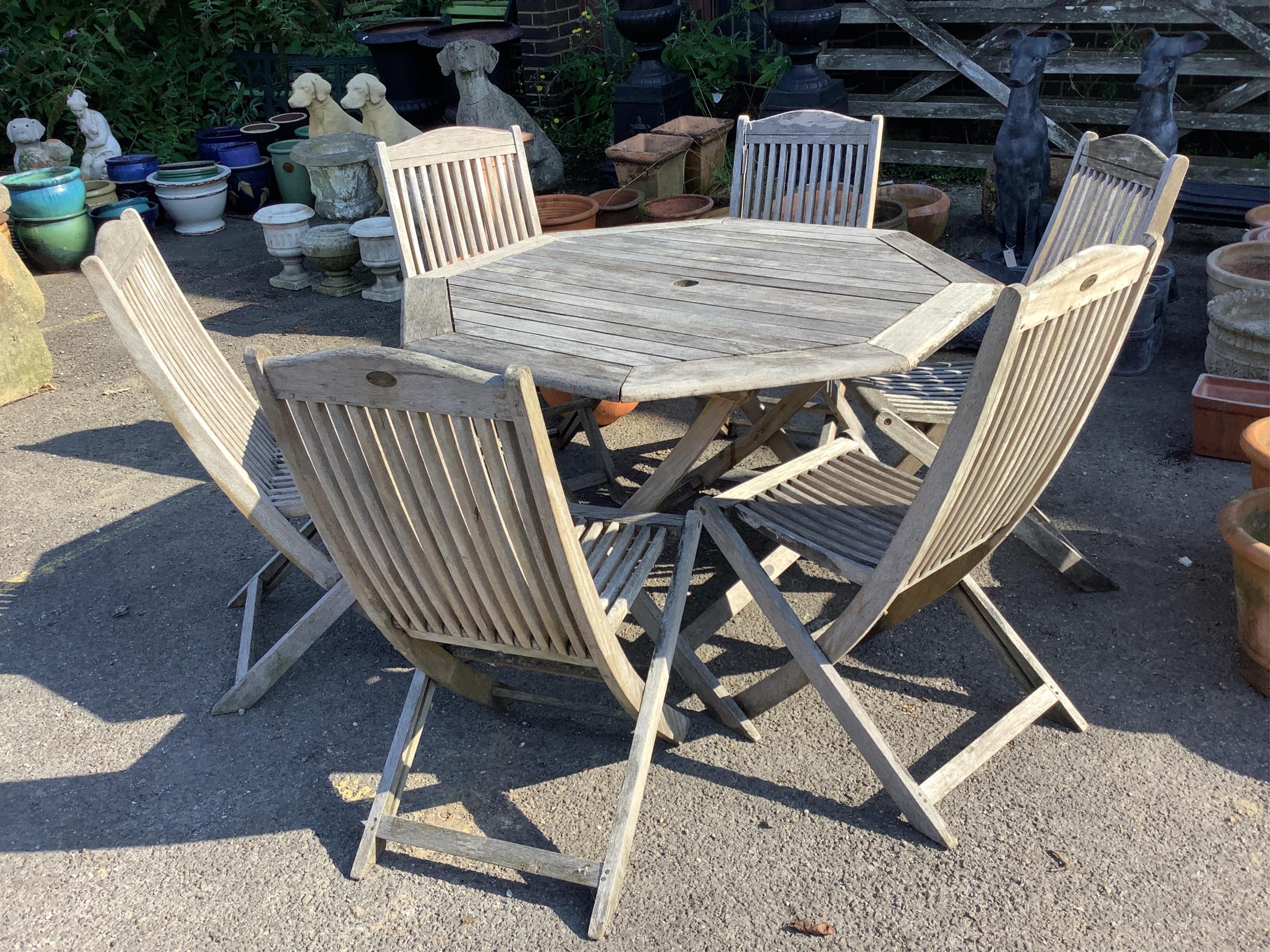 An octagonal teak folding garden table and six matching folding chairs. Condition - weathered                                                                                                                               