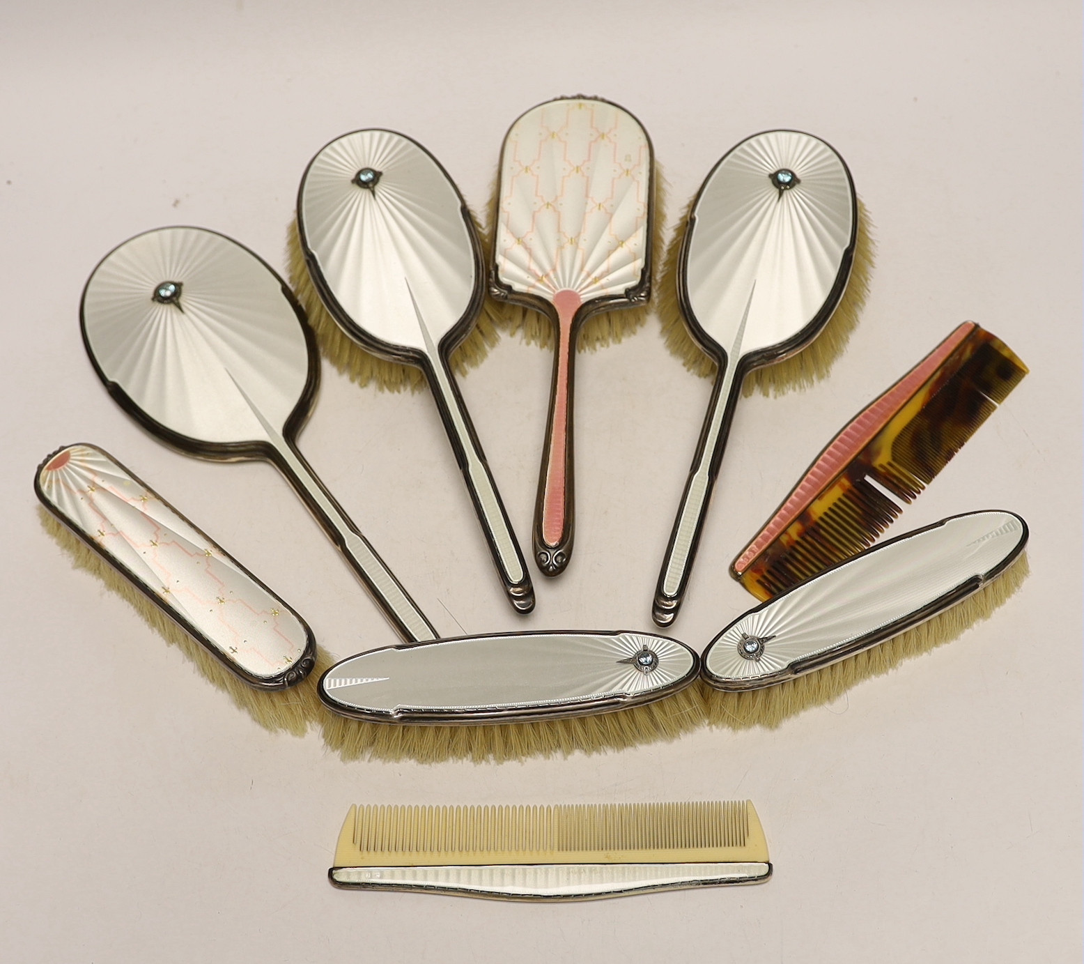 A George VI Art Deco silver, guilloche enamel, blue zircon and marcasite set five piece mirror and brush set and similar enamelled comb, Albert Carter, Birmingham, 1936/7, together with three other later silver and ename