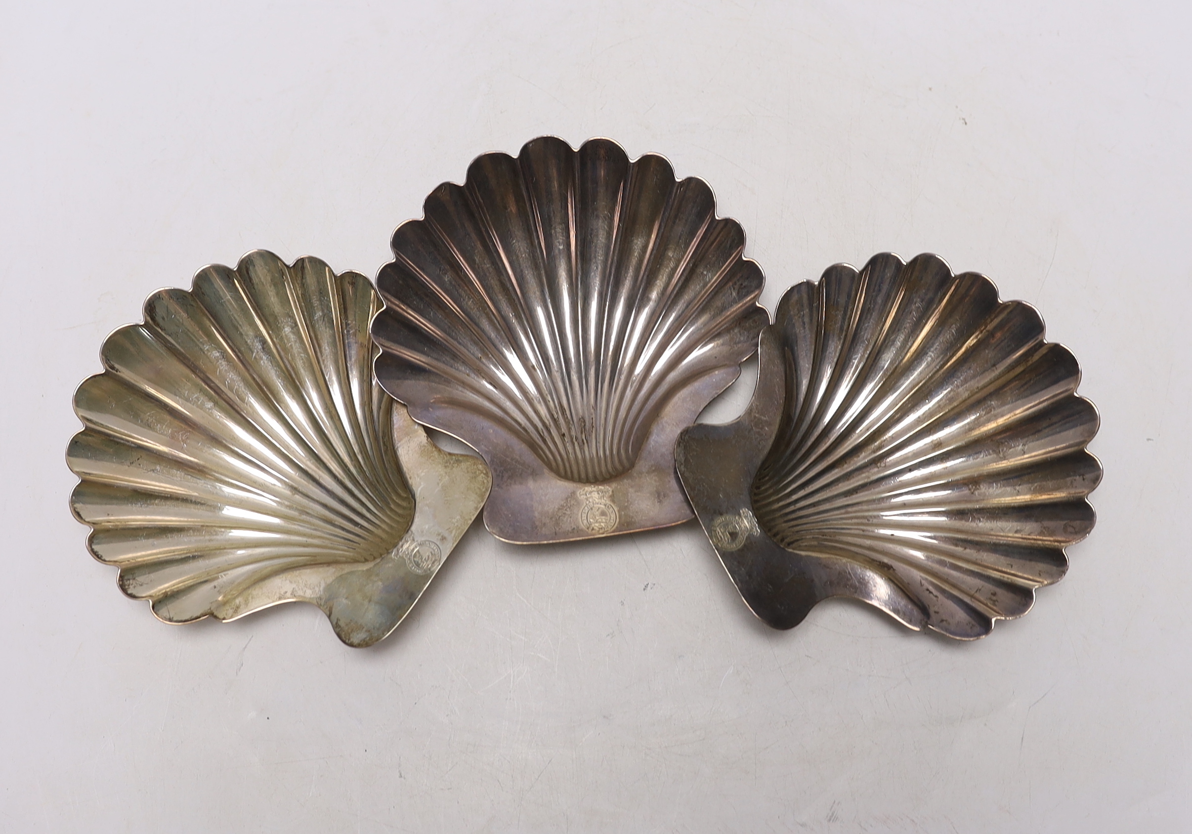 A set of three George III silver butter shells, each with engraved crest and on two shell feet, by Robert Garrard I, London, 1803, 12.8cm, 9.7oz.                                                                           