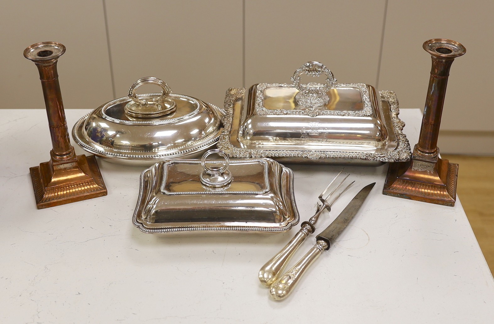 Three silver plated entrée dishes, a pair of candlesticks and a carving knife and fork, largest dish, 32 cms wide                                                                                                           