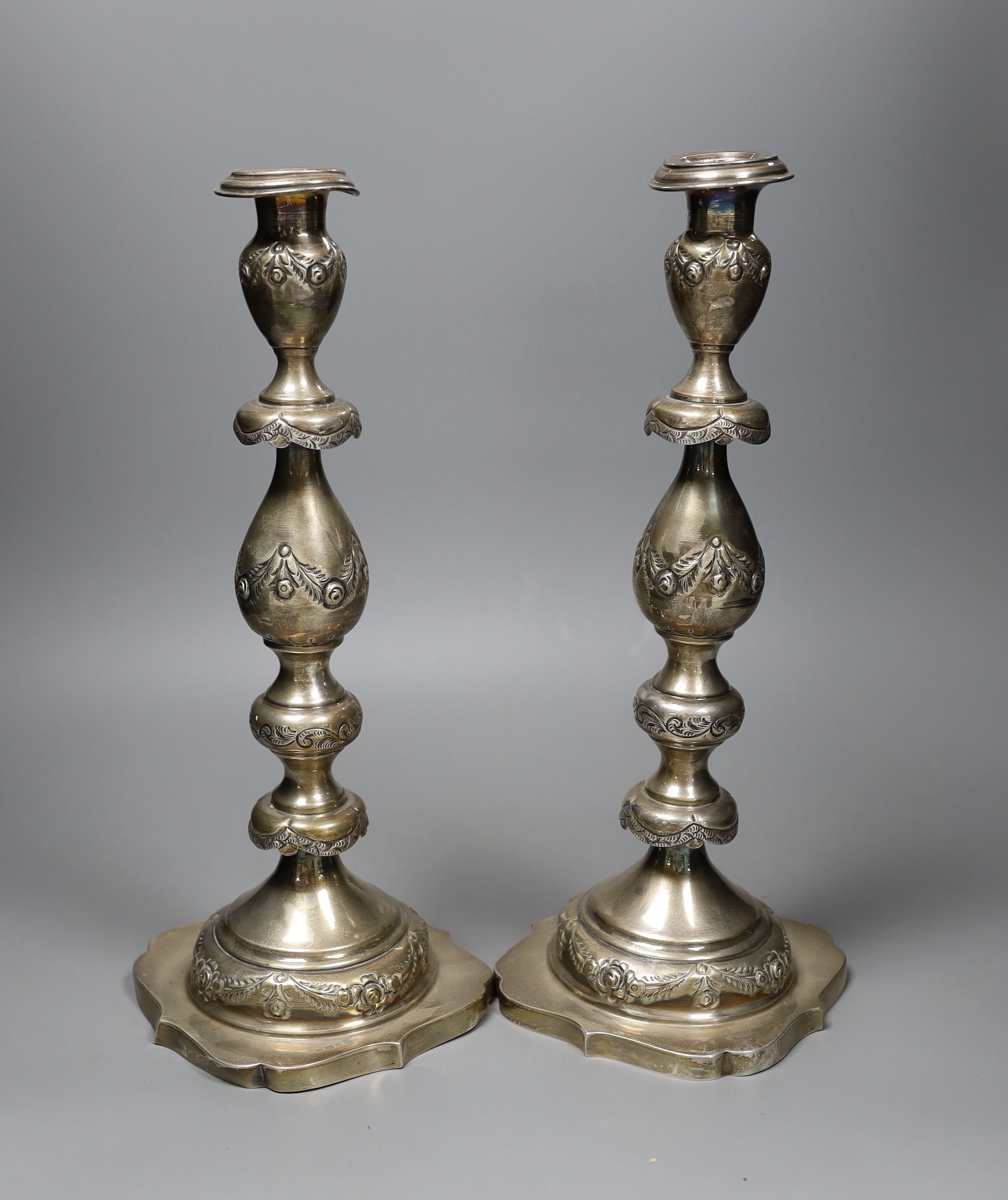 A pair of George V silver candlesticks, with floral swagged knopped stems, London 1924, 36cm, 30.5 oz.                                                                                                                      