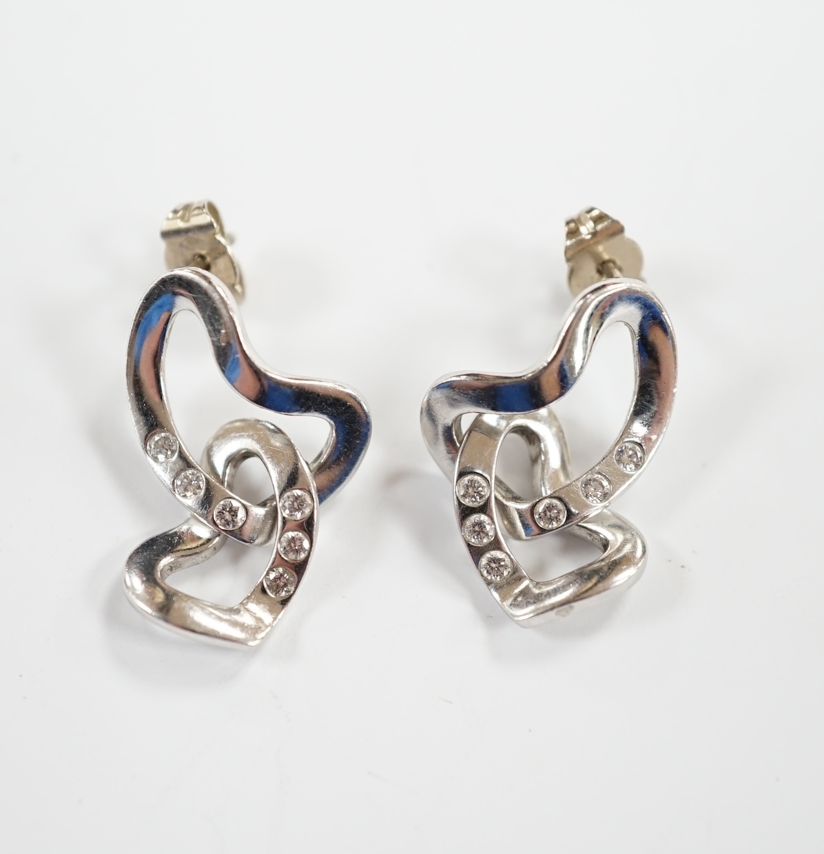 A modern pair of Georg Jensen Danish 750 white metal and diamond chip set drop earrings, or twisted heart form, drop 24mm, gross weight 7.3 grams.                                                                          
