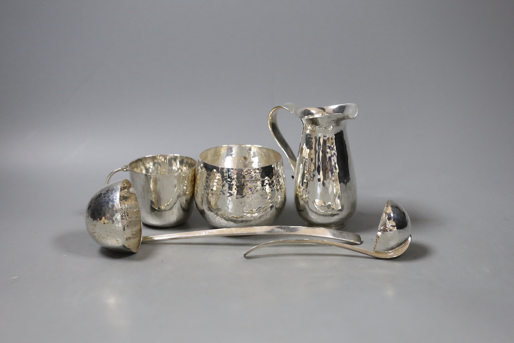 Five modern planished silver items by Pruden & Smith, including a bowl, a mug, a jug and two ladles, jug 10.9cm, 18oz.                                                                                                      