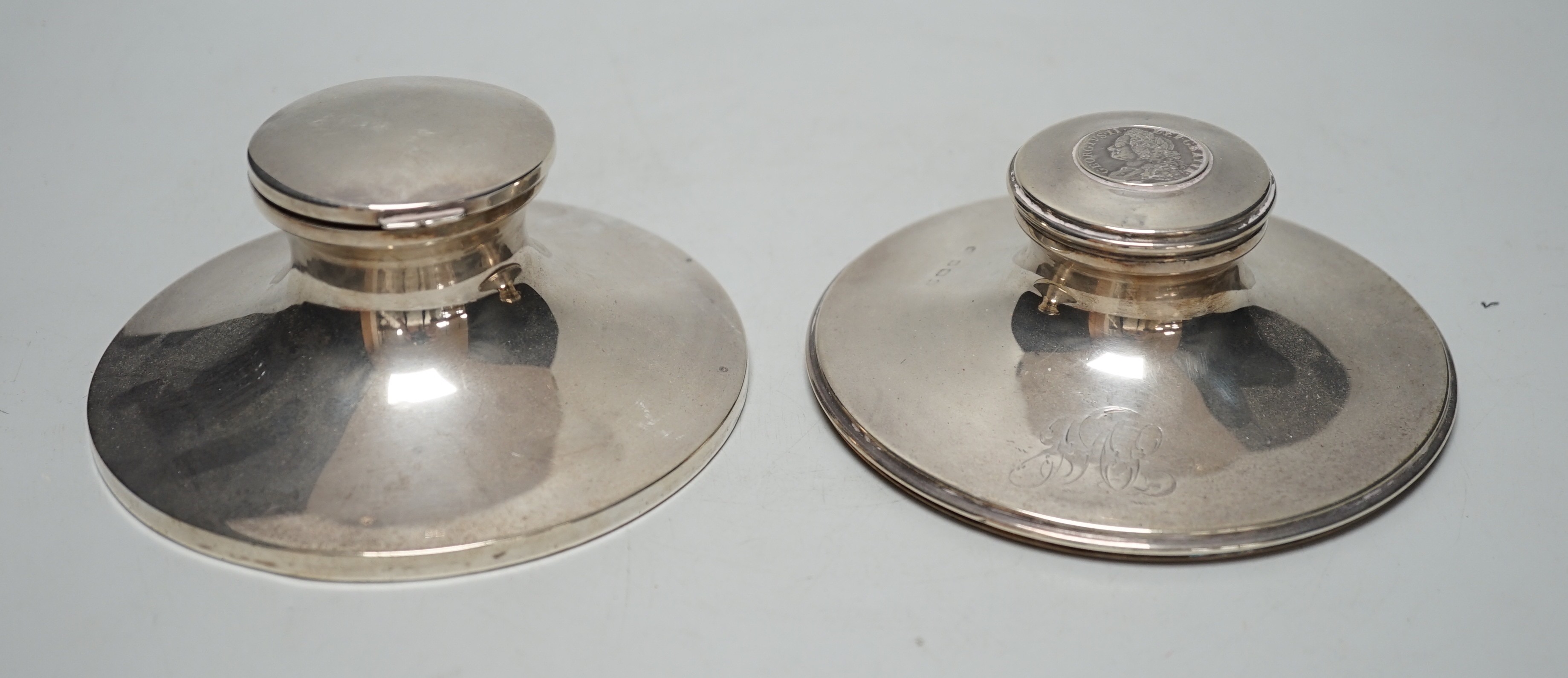 A George V silver mounted capstan inkwell, by Mappin & Webb, London, 1916, diameter 13.6cm and one other silver mounted capstan inkwell.                                                                                    