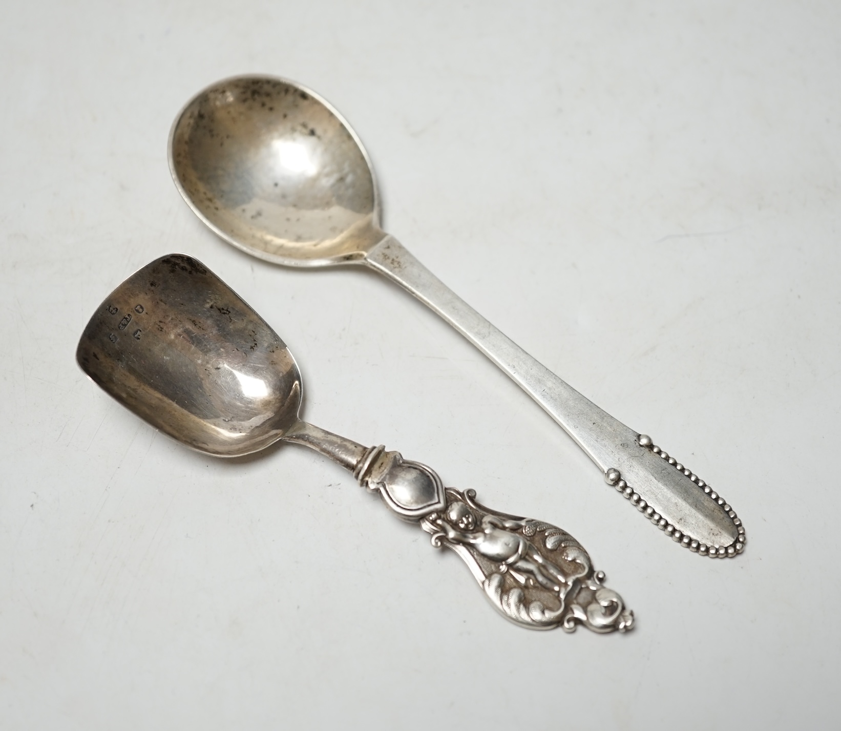 A George IV silver caddy spoon, Taylor & Perry, Birmingham, 1829, 11.4cm, together with a George V silver Georg Jensen spoon, import marks for London, 1923. Condition - fair                                               