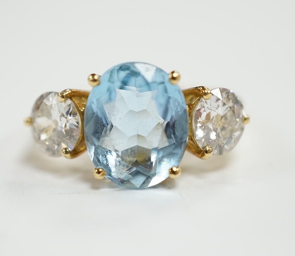 A modern 18ct gold, single stone oval cut aquamarine and two stone round brilliant cut diamond set ring, size L, gross weight 4.8 grams.                                                                                    
