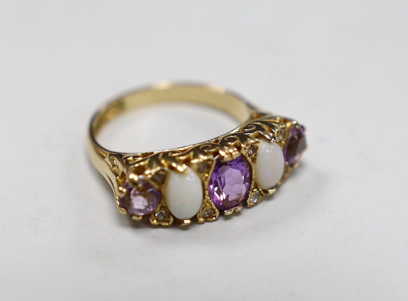 A modern 9ct gold, three stone amethyst and two stone white opal set half hoop ring, with white stone chip spacers, size L/M, gross weight 5 grams.                                                                         