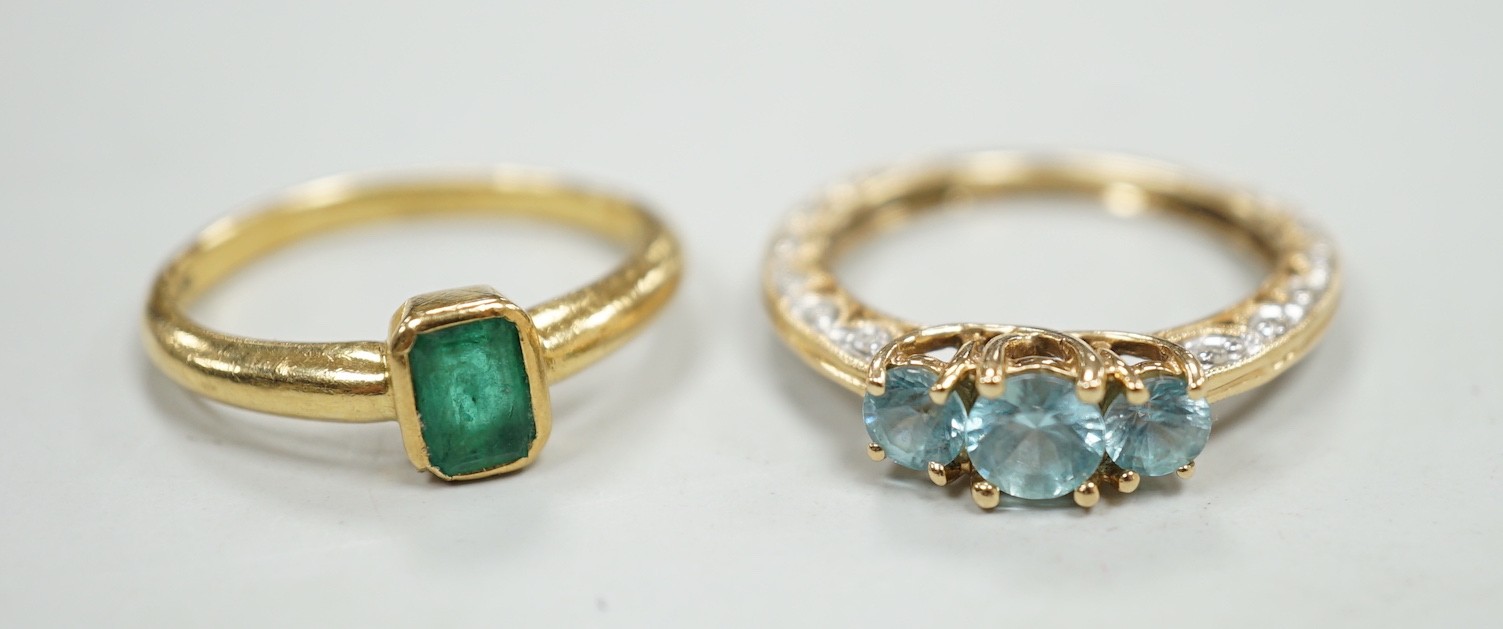 A modern 18ct gold and single stone emerald set ring, size M, gross weight 4 grams and a modern 14k and three stone blue zircon dress ring, with diamond chip set shank, size P, gross weight 3.4 grams.                    