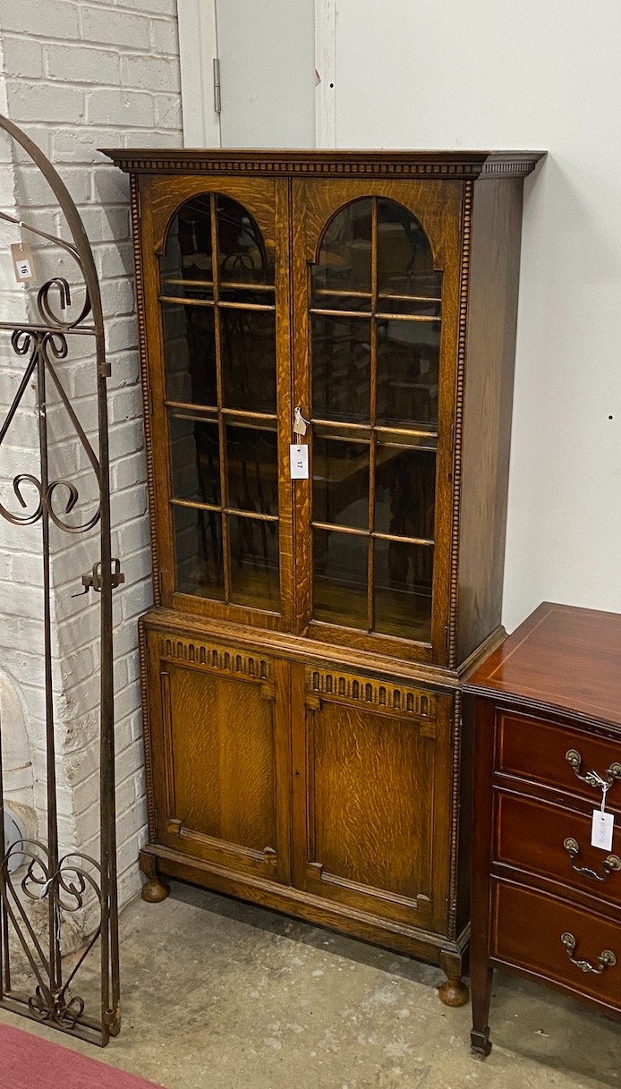 A 1920's glazed oak two door glazed cabinet, width 80cm, depth 30cm, height 175cm                                                                                                                                           