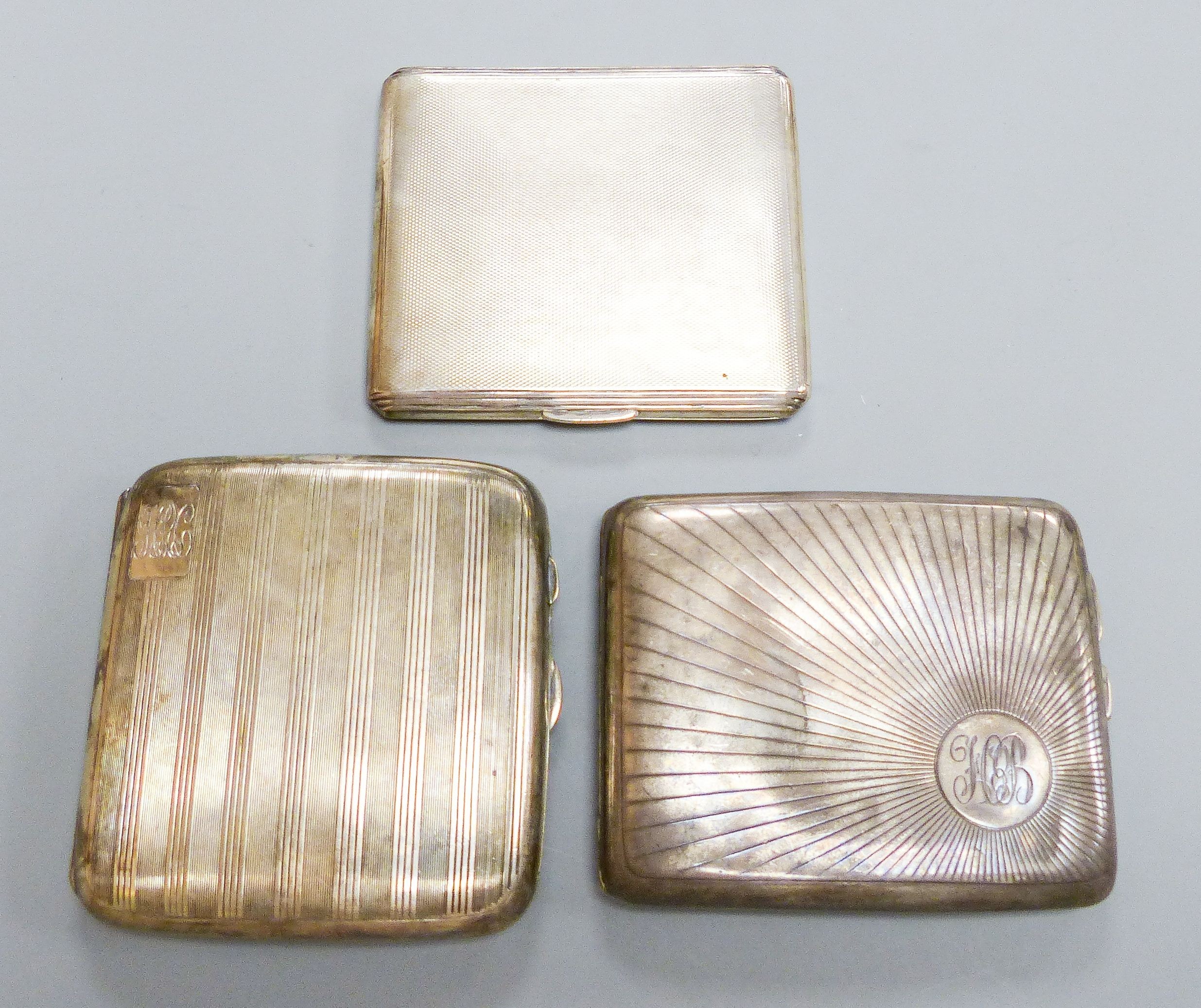 Three assorted George V silver cigarette cases, largest 9.8cm, gross weight 11.5oz.                                                                                                                                         