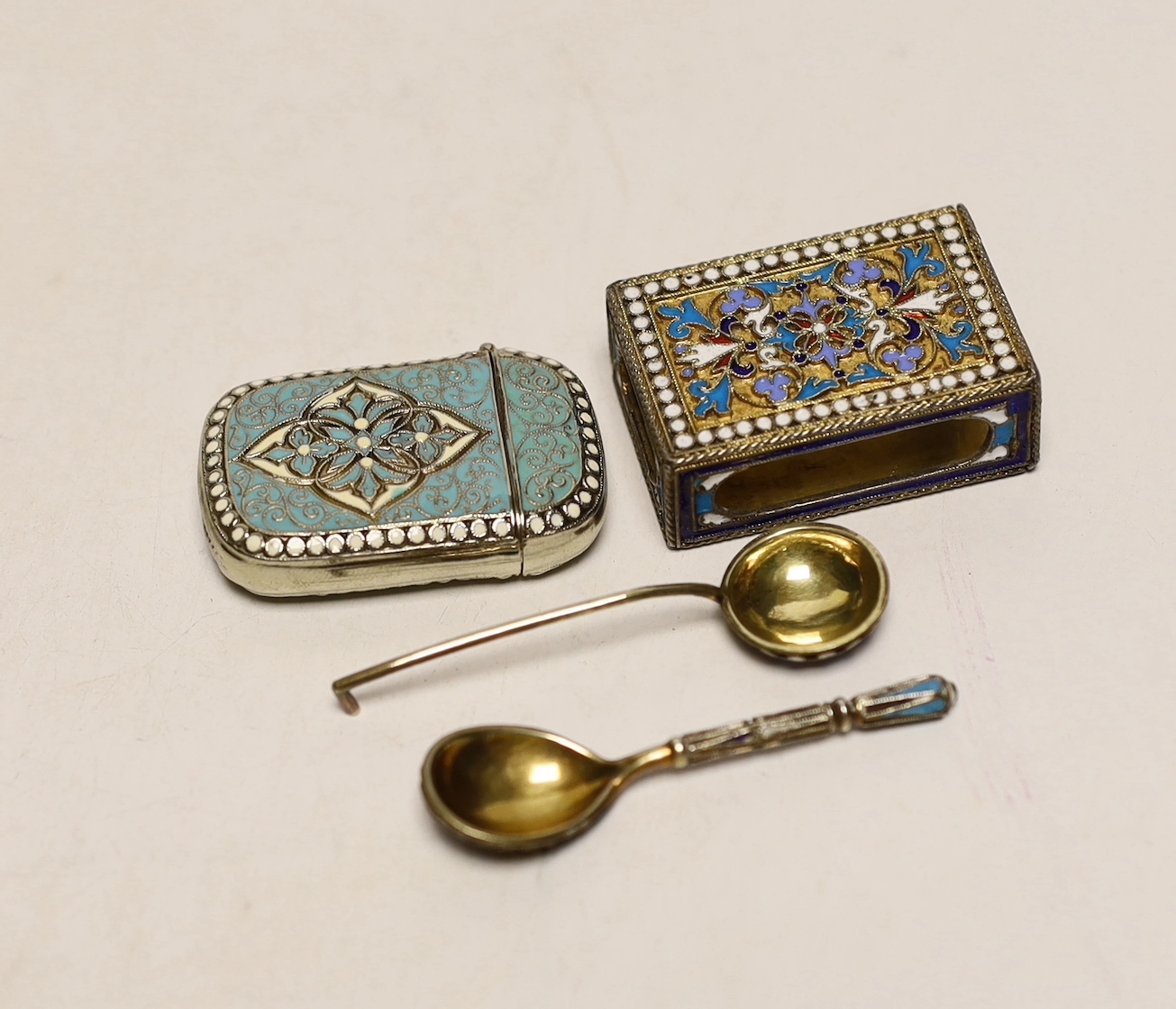 A 20th century Norwegian white metal and enamelled vesta case, by Marius Hammer, 47mm, together with two white metal and cloisonné enamel condiment spoons and a matchbox holder.                                           