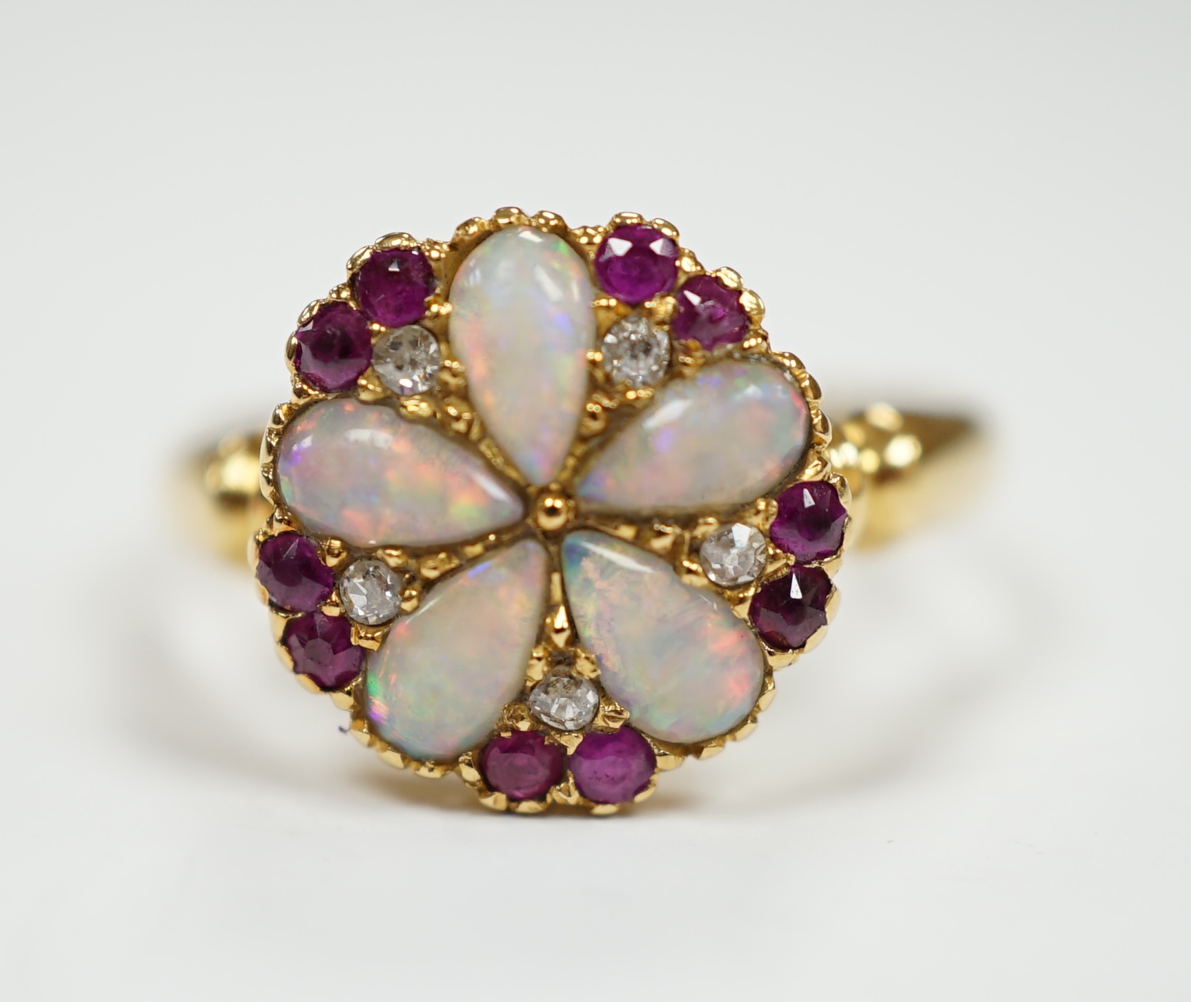 An Edwardian 18ct gold, white opal, ruby and diamond cluster set ring, size K, gross weight 3.1 grams.                                                                                                                      