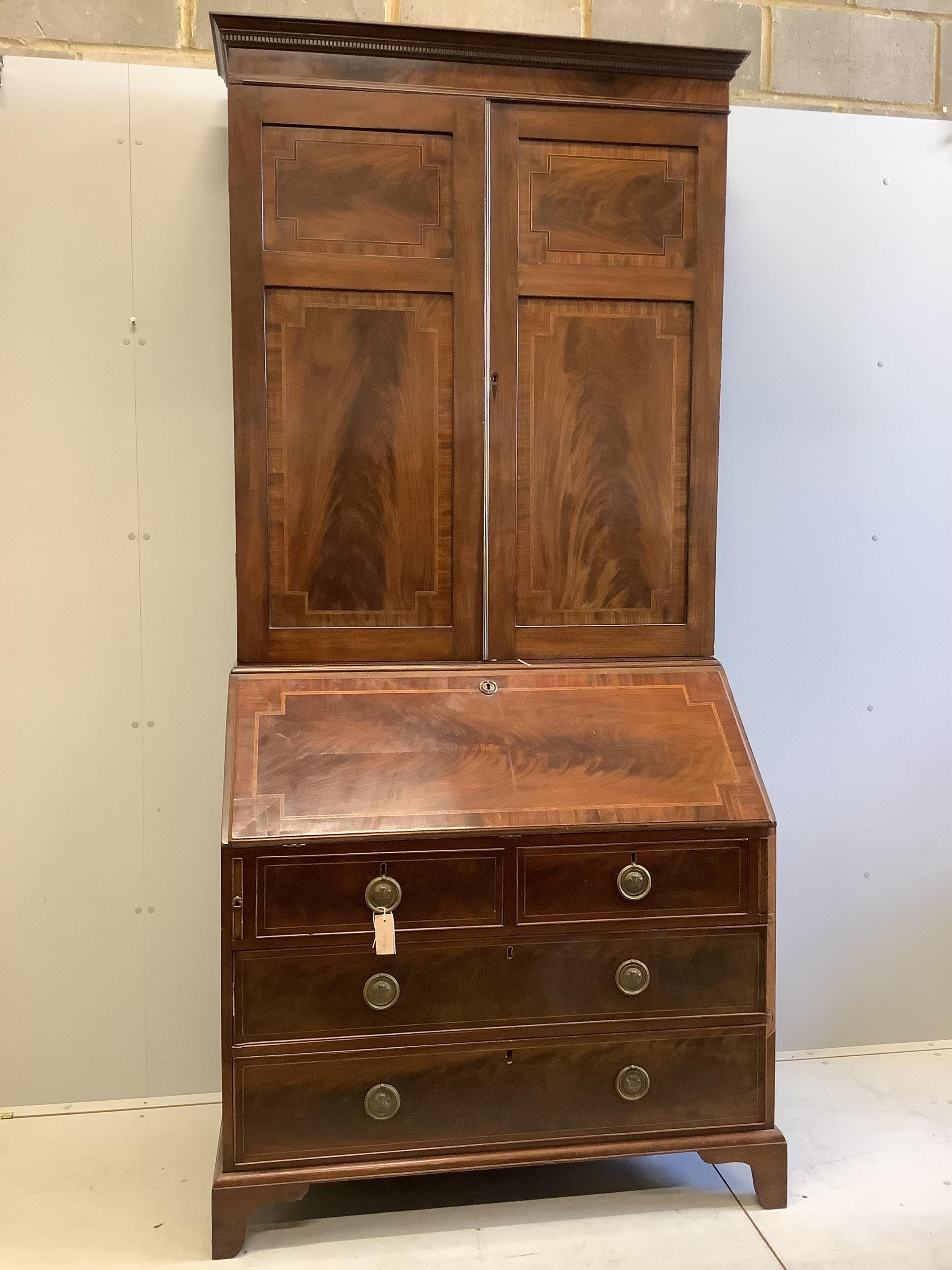 A late Georgian mahogany bureau bookcase crossbanded and inlaid upper section, fitted a pair of panelled doors, above full flap, fitted interior, two short and two long drawers, on square bracket feet, width 107cm, depth