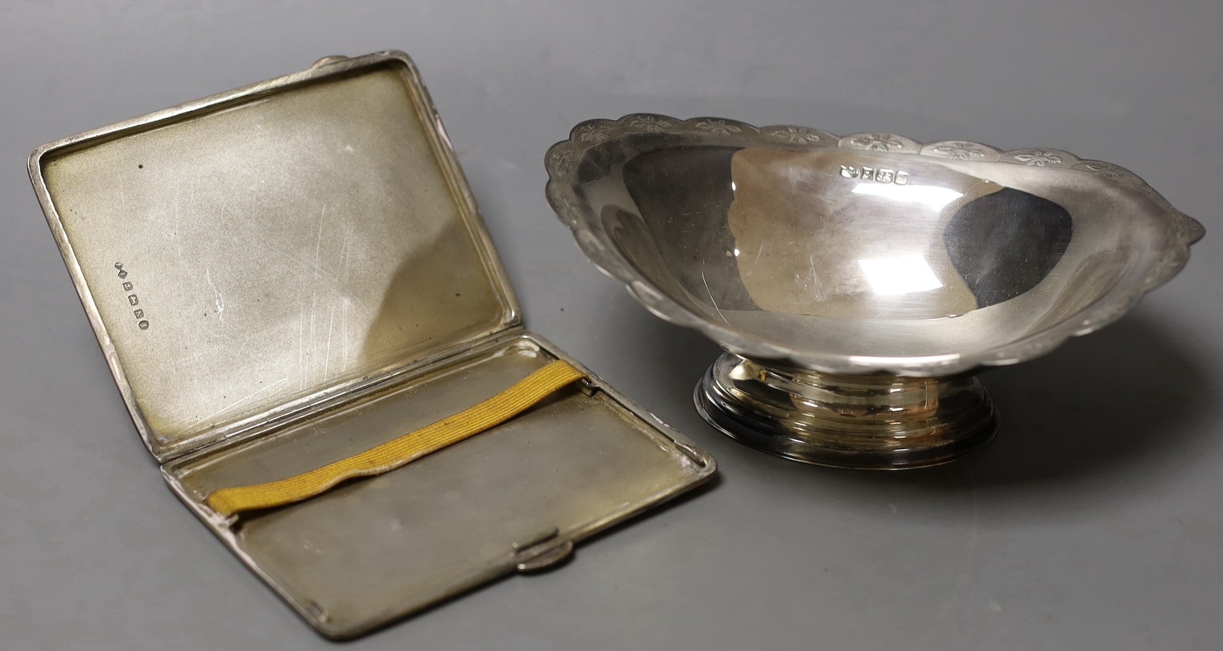 An Elizabeth II silver oval dish, with cusped border, by Mappin & Webb, Birmingham, 1985, length 16cm and an earlier engine turned silver cigarette case                                                                    