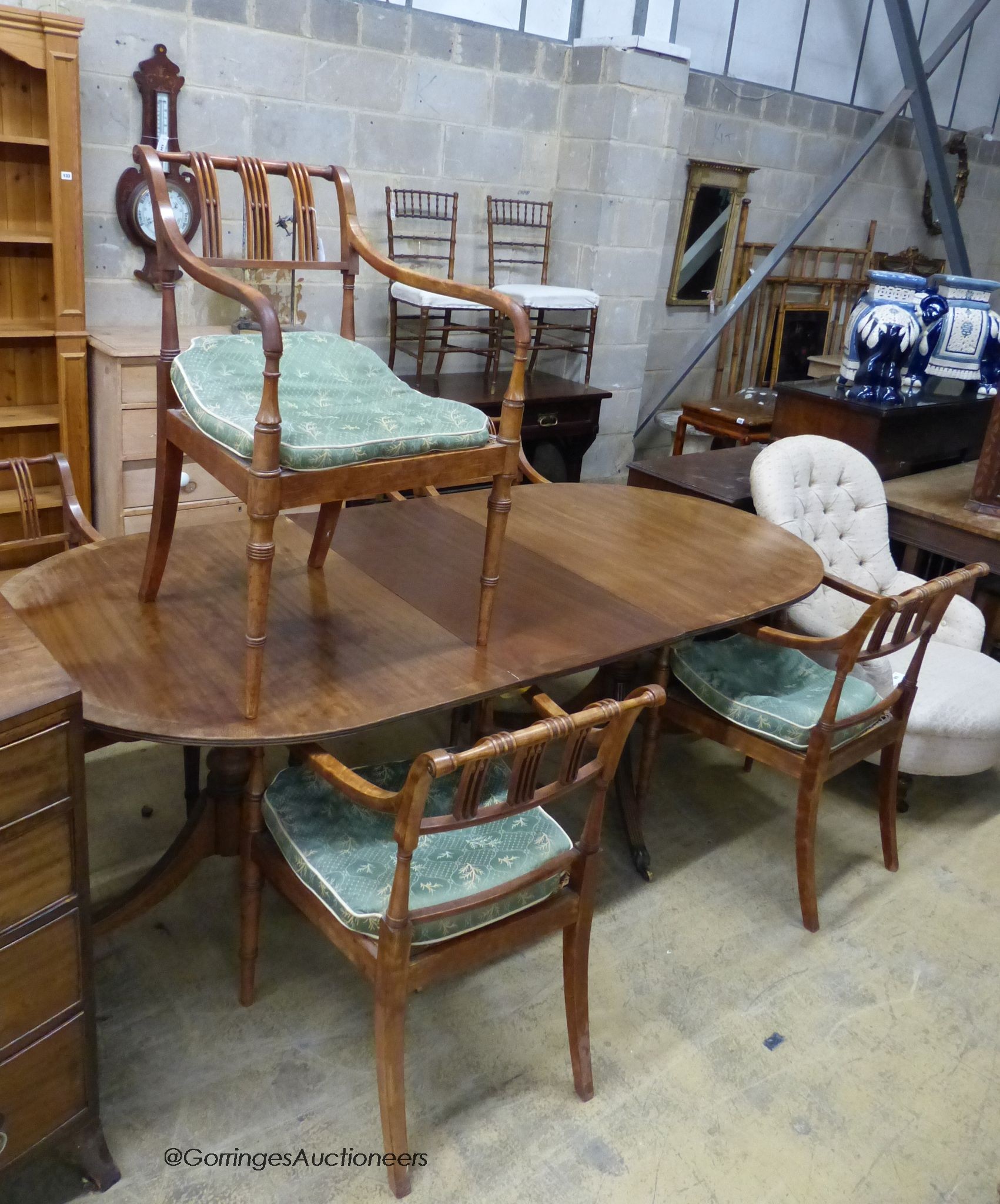 A reproduction mahogany twin pillar extending dining table and a set of six Regency fruitwood caned seated elbow chairs                                                                                                     