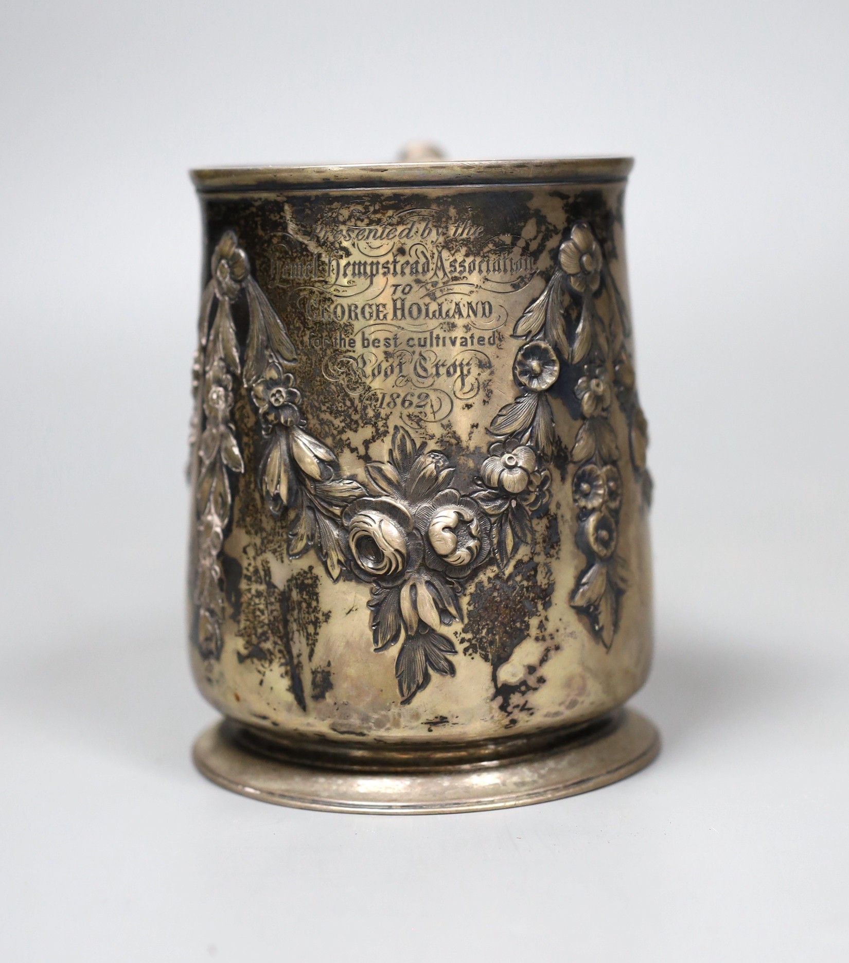 A George III silver pint mug, with later Victorian embossed and chased floral swag decoration and 1862 Agricultural Prize inscription, London 1753, 11 oz.                                                                  