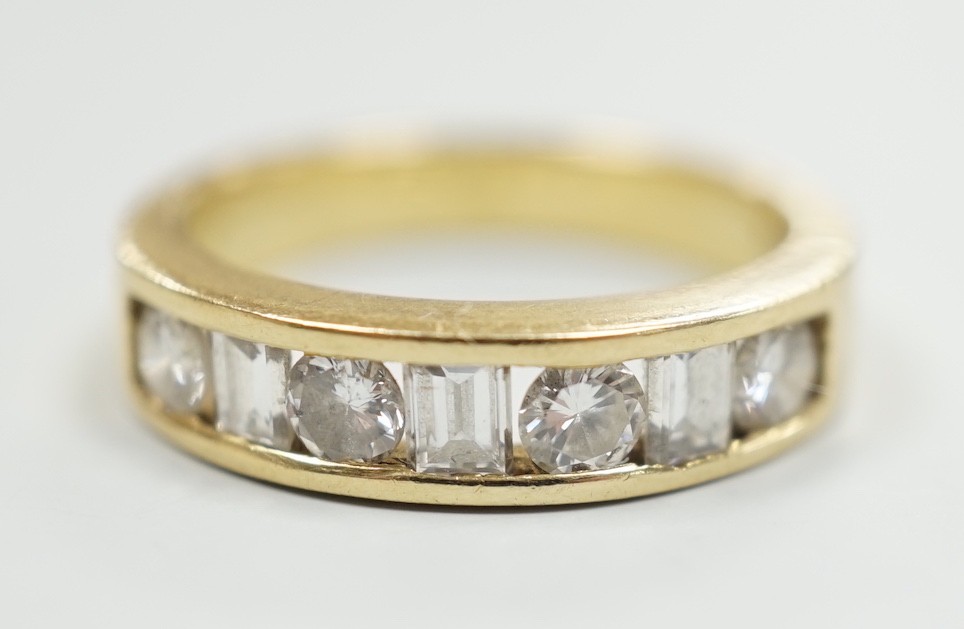 An 18k yellow metal, four stone round cut and three stone rectangular cut channel set diamond half hoop ring, size L, gross weight 4.9 grams.                                                                               