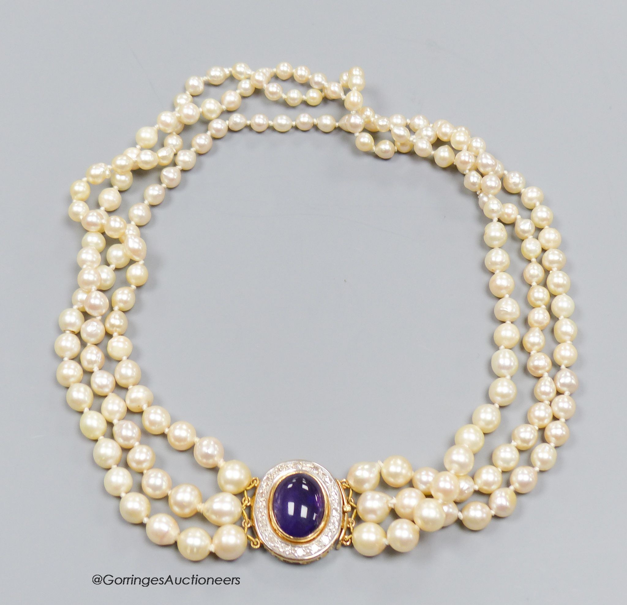 A three strand cultured pearl necklace with cabochon amethyst and diamond set 18ct gold clasp, 40cm.                                                                                                                        