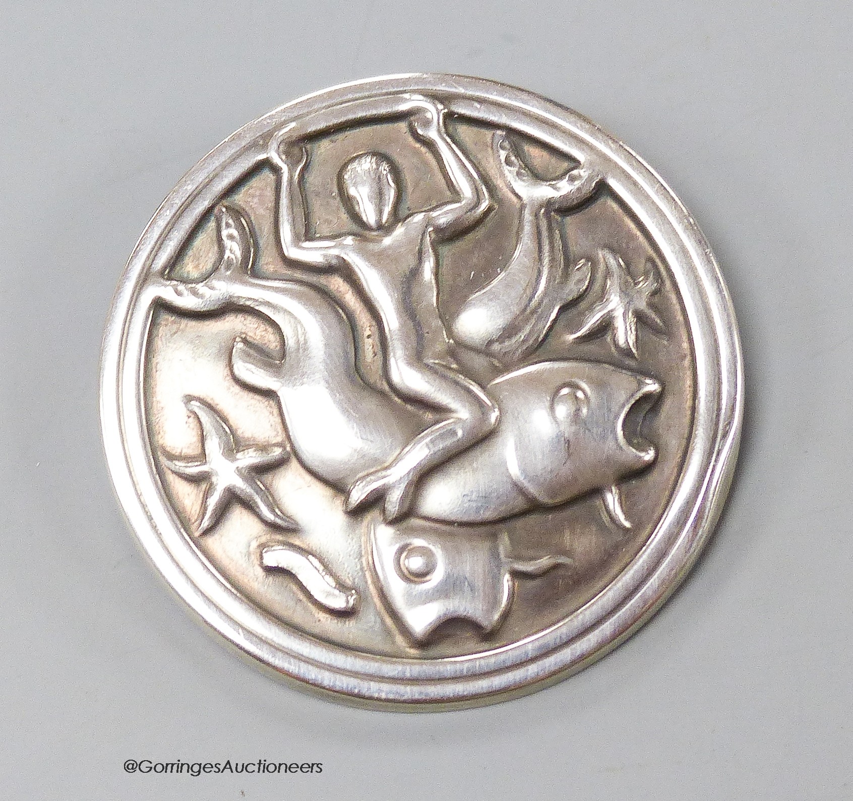 A Georg Jensen sterling circular brooch, design no. 285, depicting a man with two fish, 42mm.                                                                                                                               