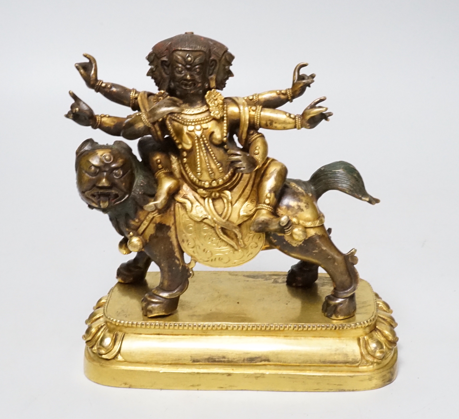 A Sino-Tibetan gilt bronze group of a deity on lionback, 15cm wide                                                                                                                                                          