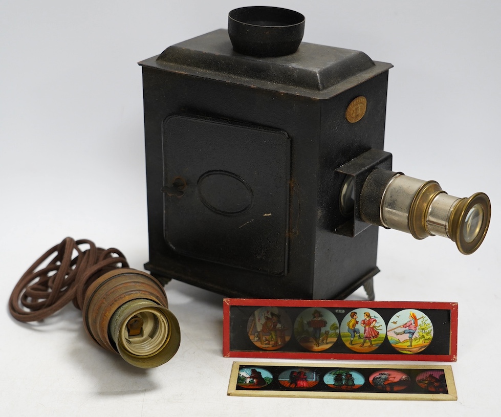 A late 19th century child's tinplate magic lantern with a selection of German slides, magic lantern 21cm high. Condition - fair to good                                                                                     