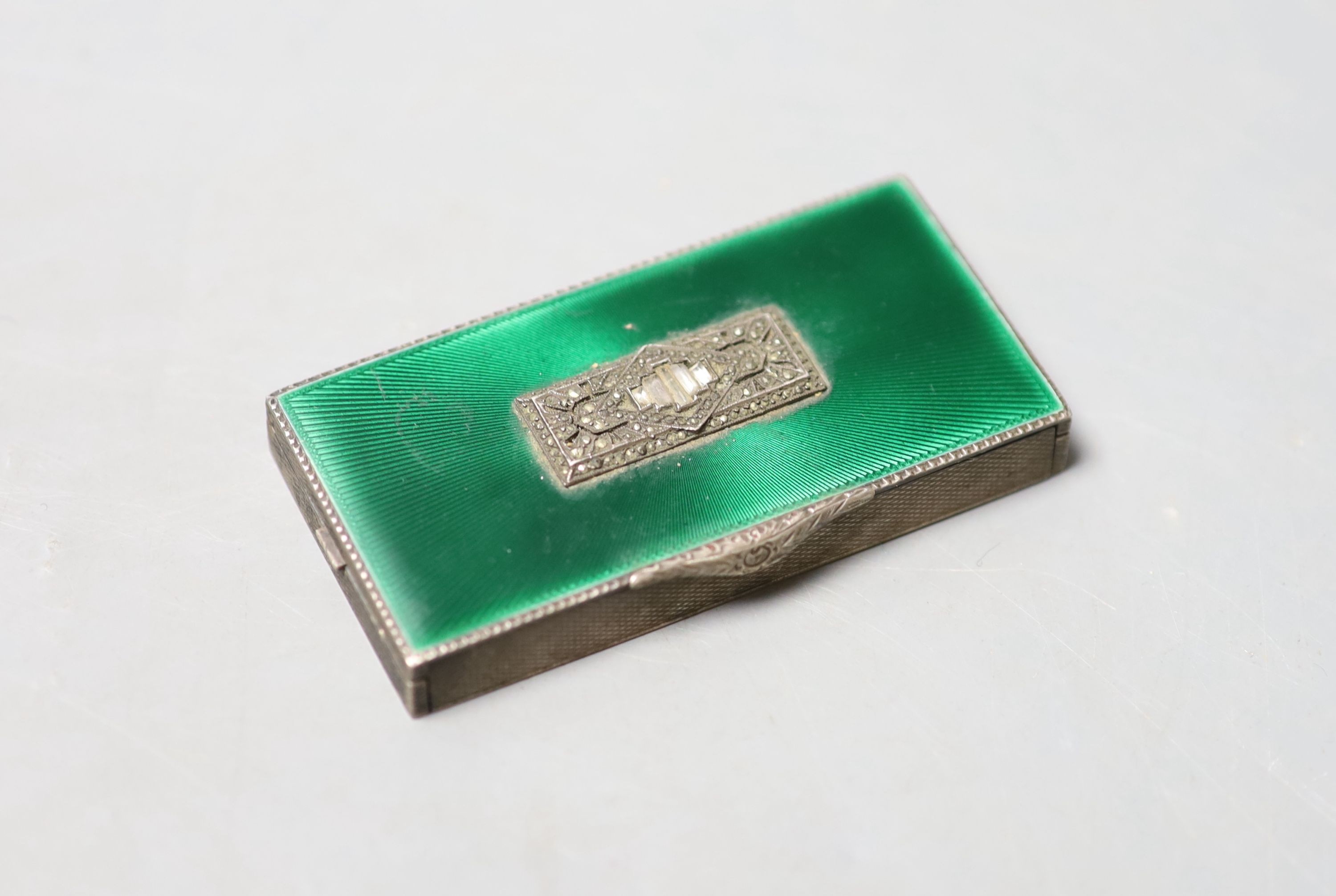 A 1930's engine turned silver, green enamel, marcasite and paste set minaudiere, lacking mirror and lipstick, import marks for George Stockwell, London, 1931, 8cm.                                                         